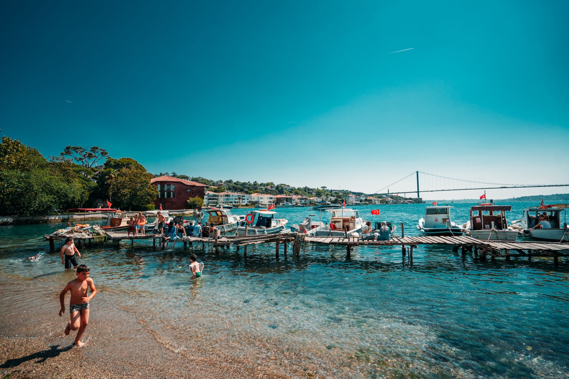 A family enjoys a sunny day by the Bosphorus with boats docked nearby and scenic views.