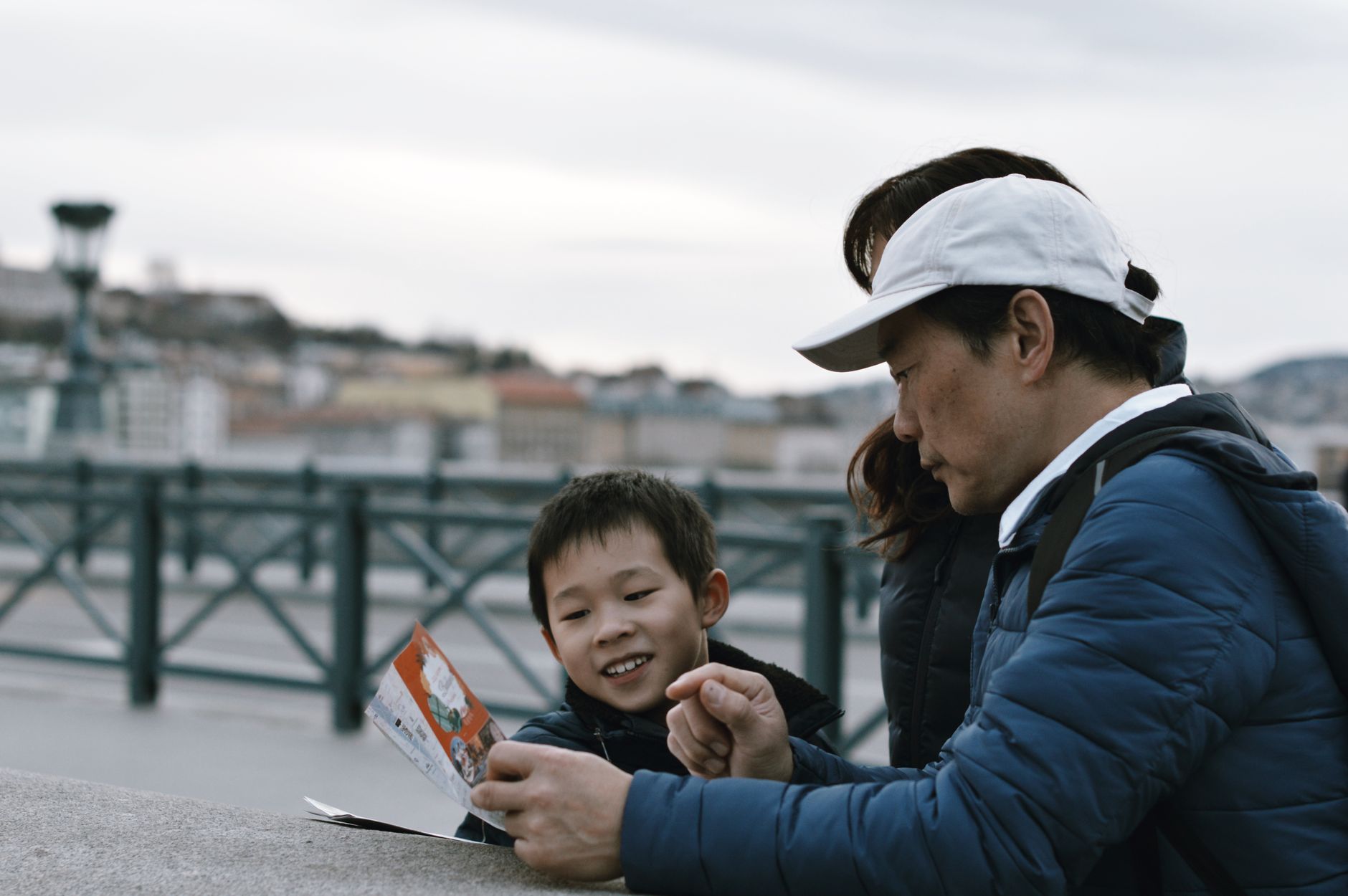 A man and a boy examining a map together, enjoying their day out.