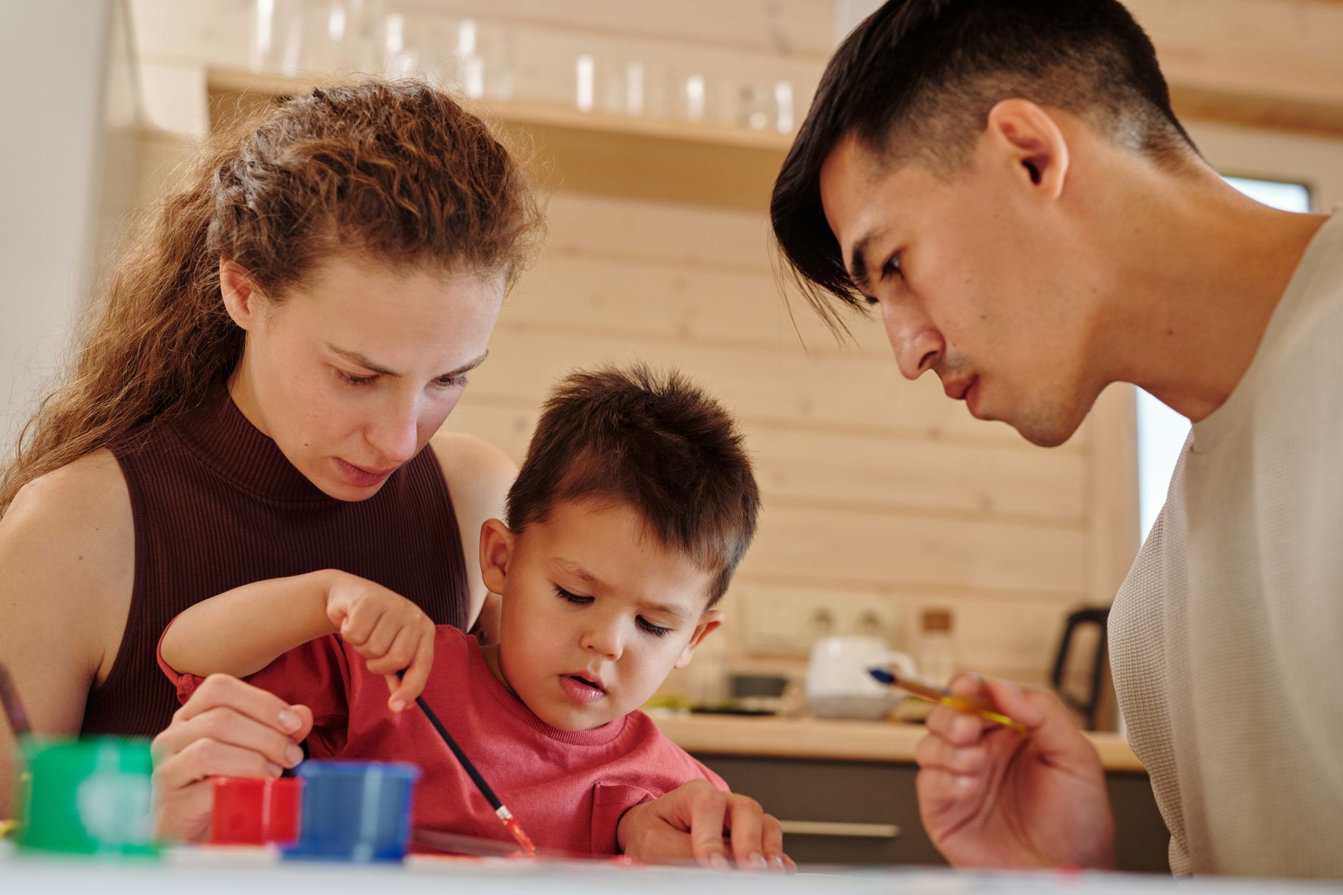 A parent and child engaged in a creative painting activity at home, focusing on learning and therapy.
