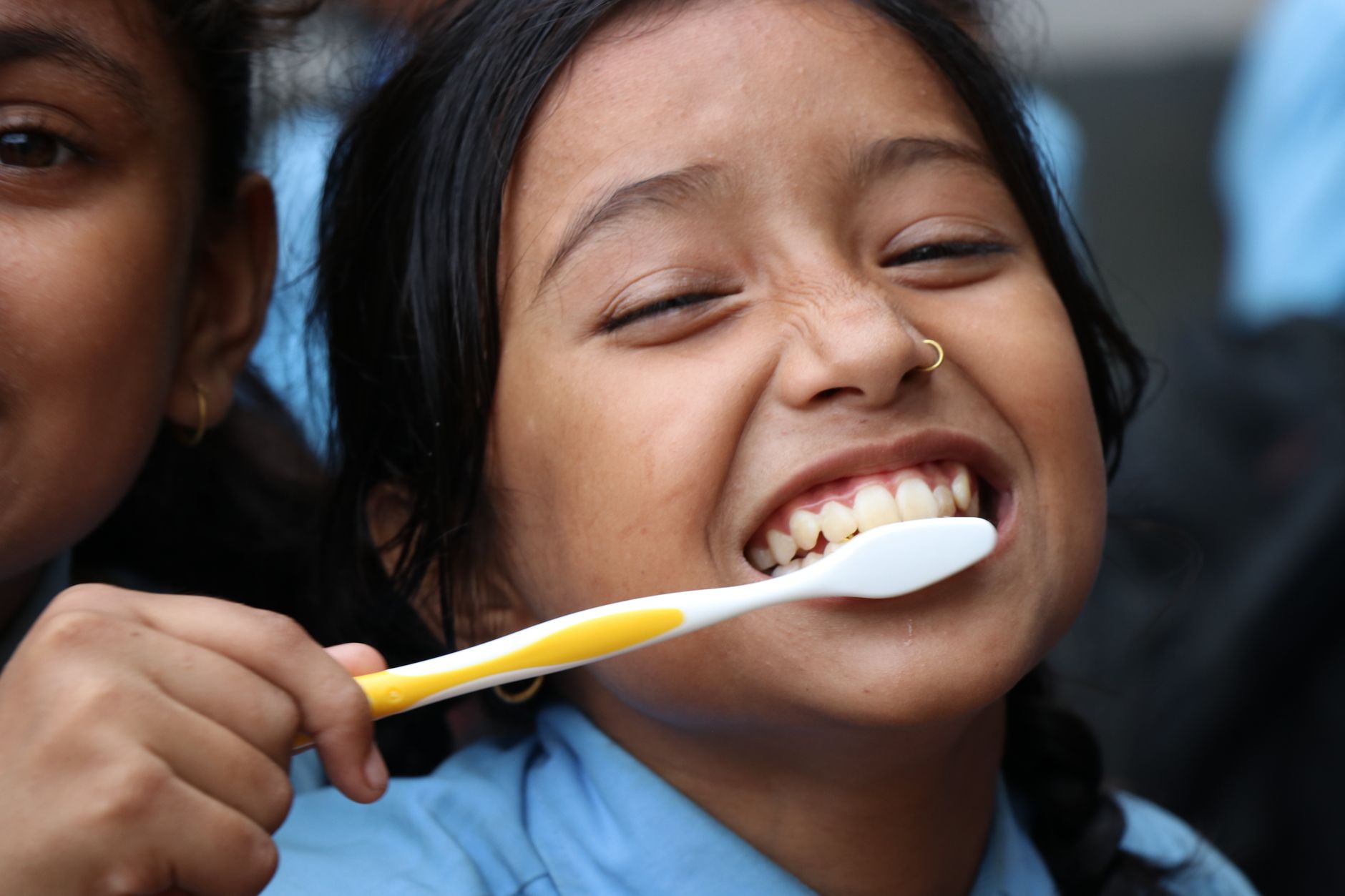 A young girl smiling while holding a toothbrush, excited about dental hygiene.