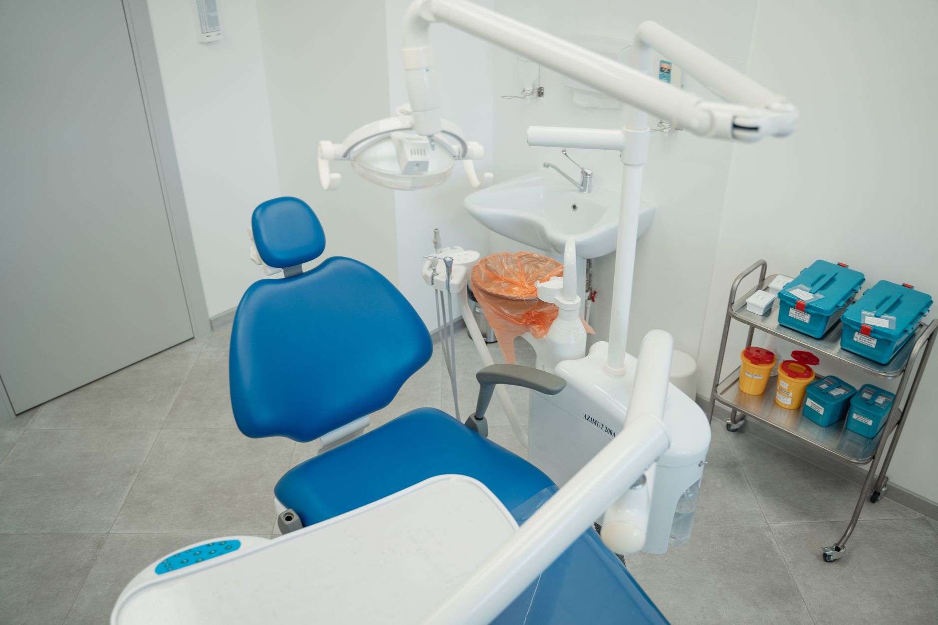 Interior of a dental clinic featuring a blue dental chair and equipment.