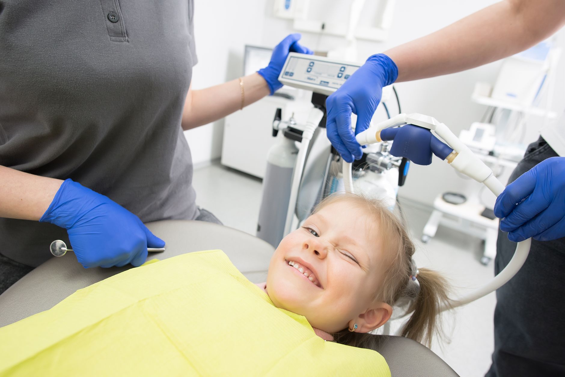 A young girl smiles during a dental visit, exploring sedation options with a dentist.