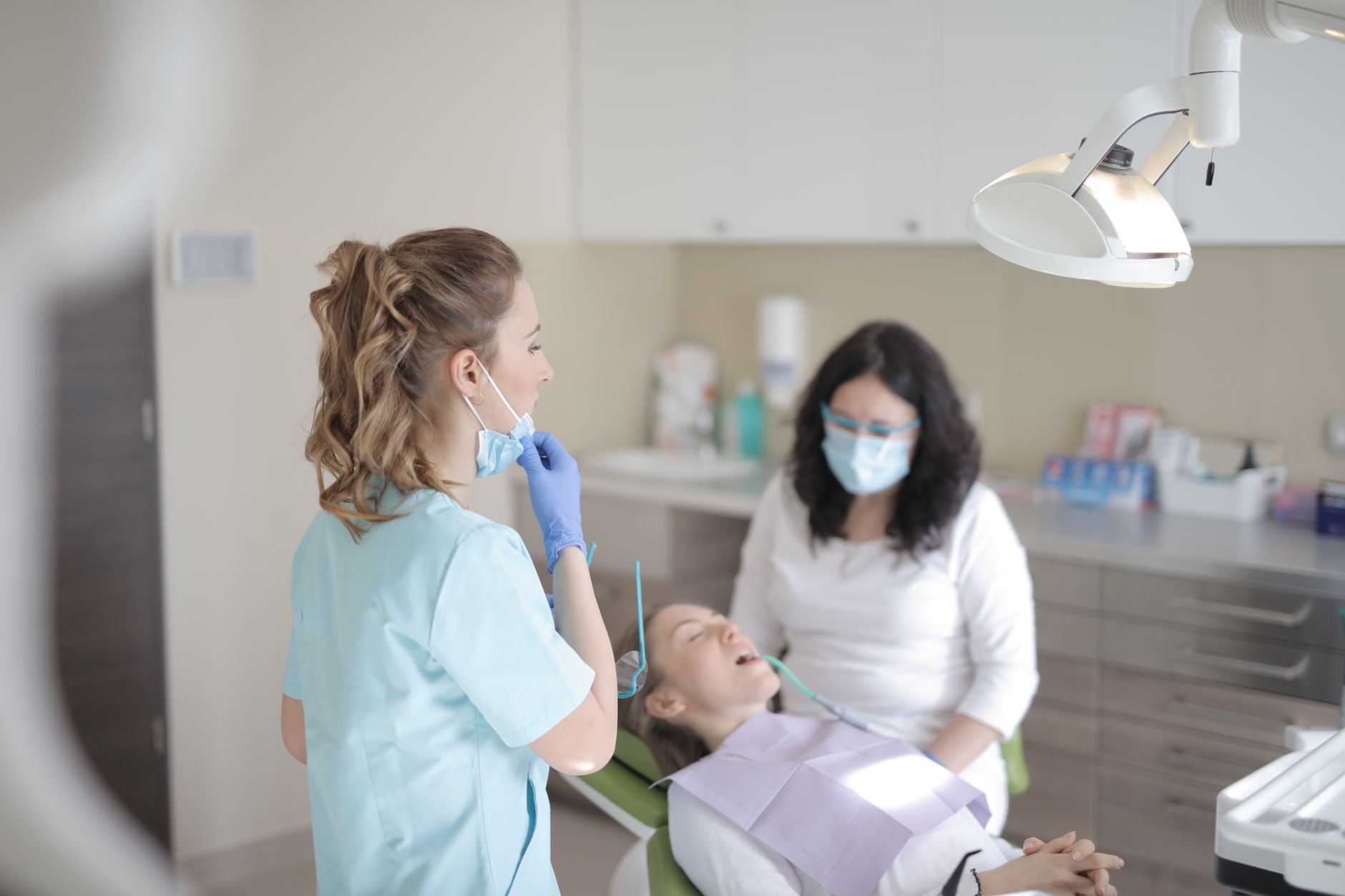 Two siblings sitting in dental chairs in a clinic, smiling while receiving dental care.