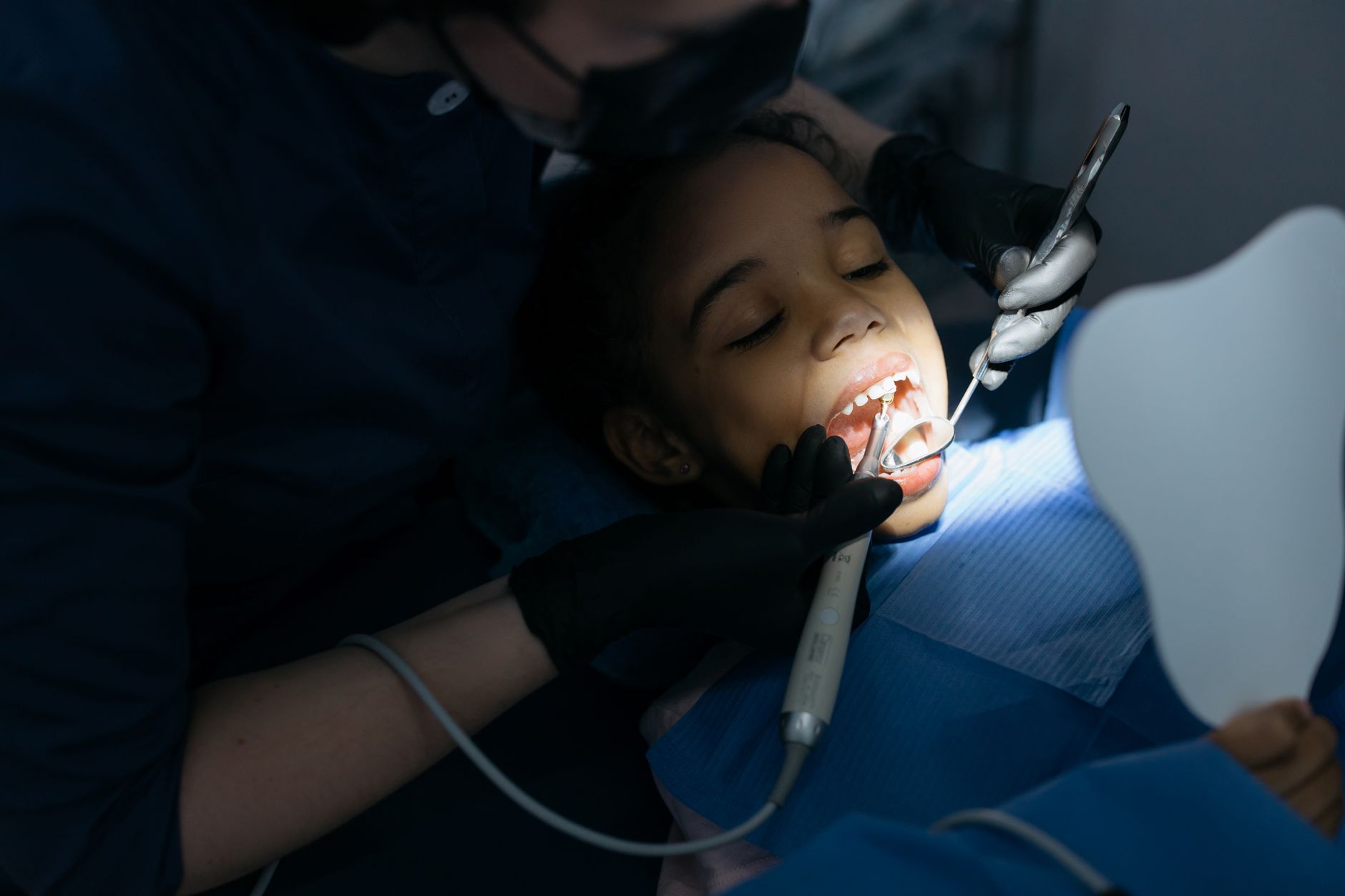 A pediatric dentist examines a child's teeth in a Turkish clinic.