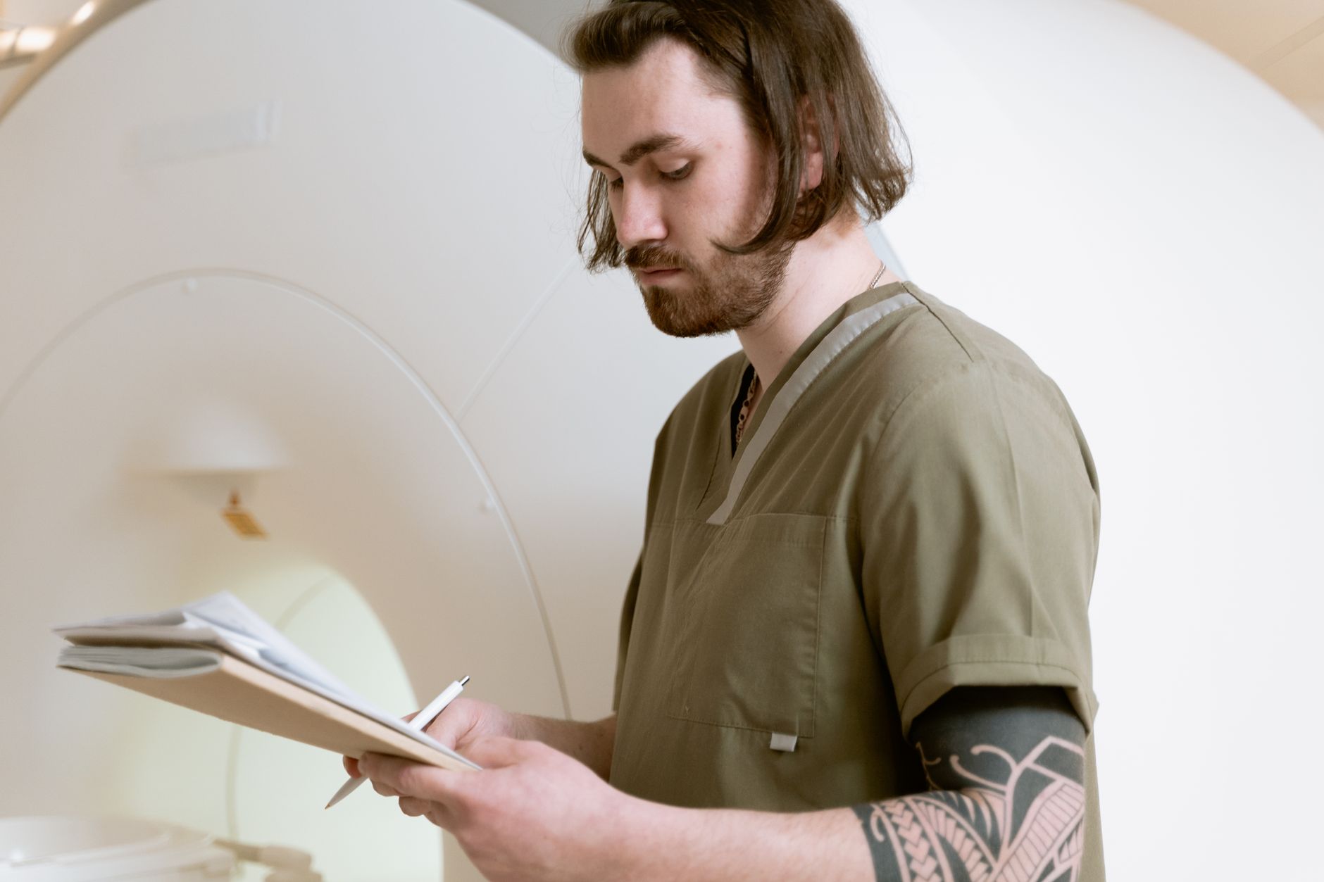 A healthcare worker in scrubs, focused on notes, in an imaging room.