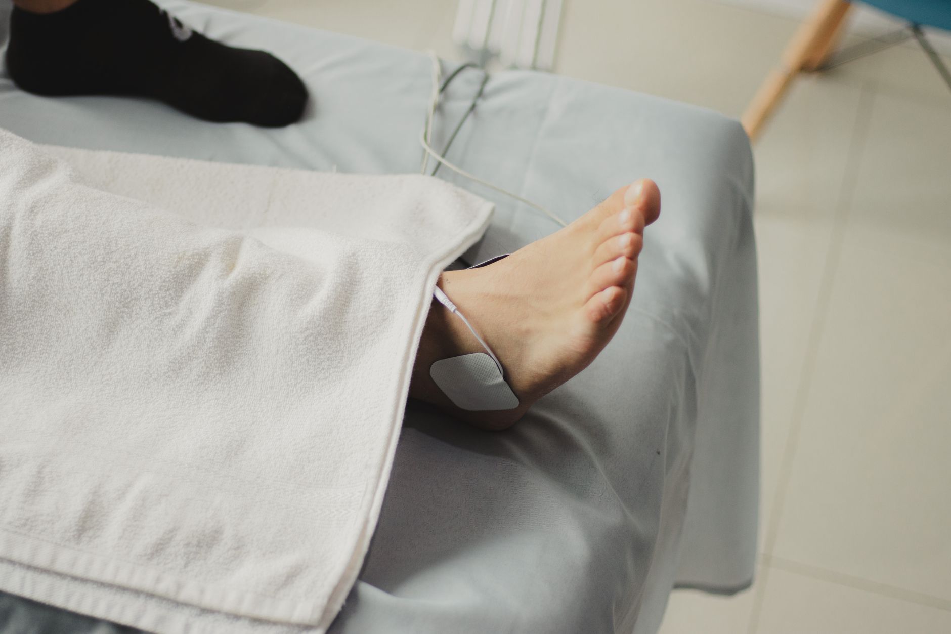 A child's foot with an electrode pad receiving physiotherapy treatment in a clinical setting.