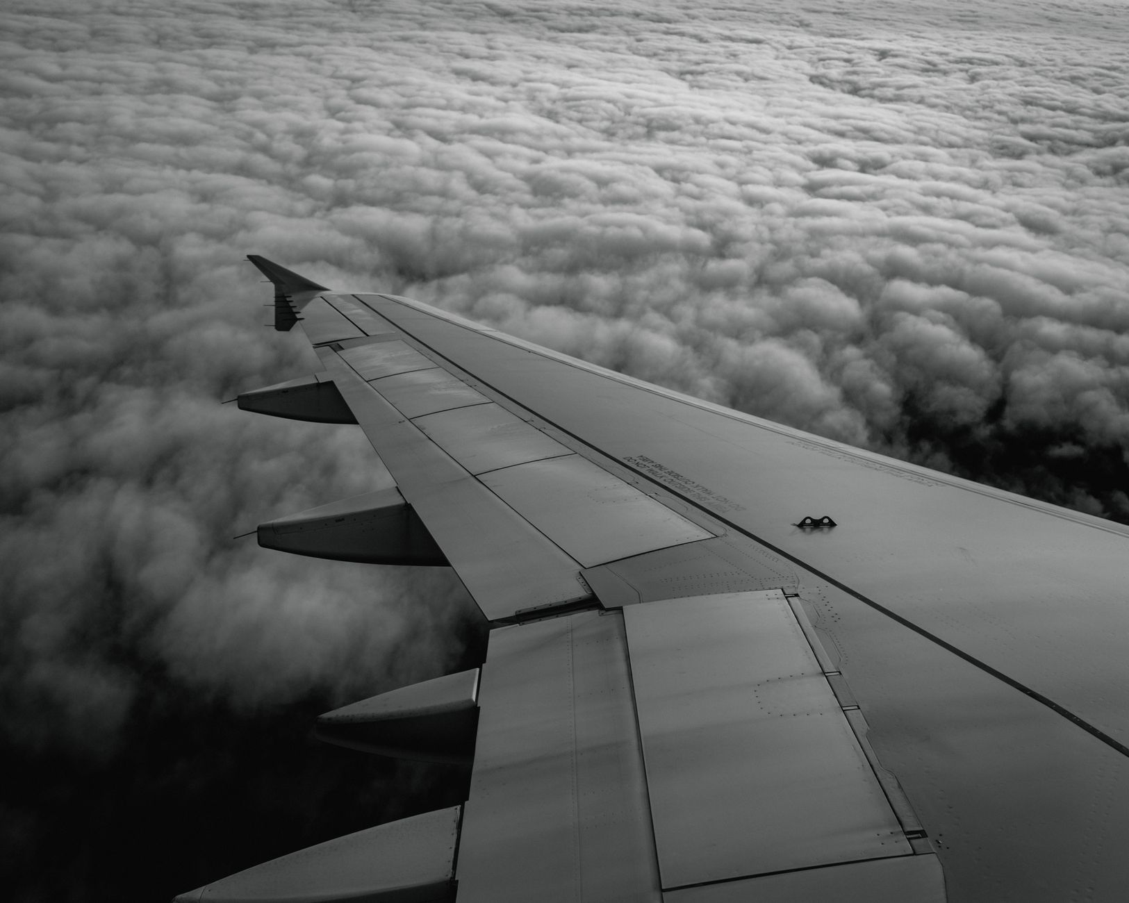 View of an airplane wing flying above fluffy clouds, symbolizing a safe return home.