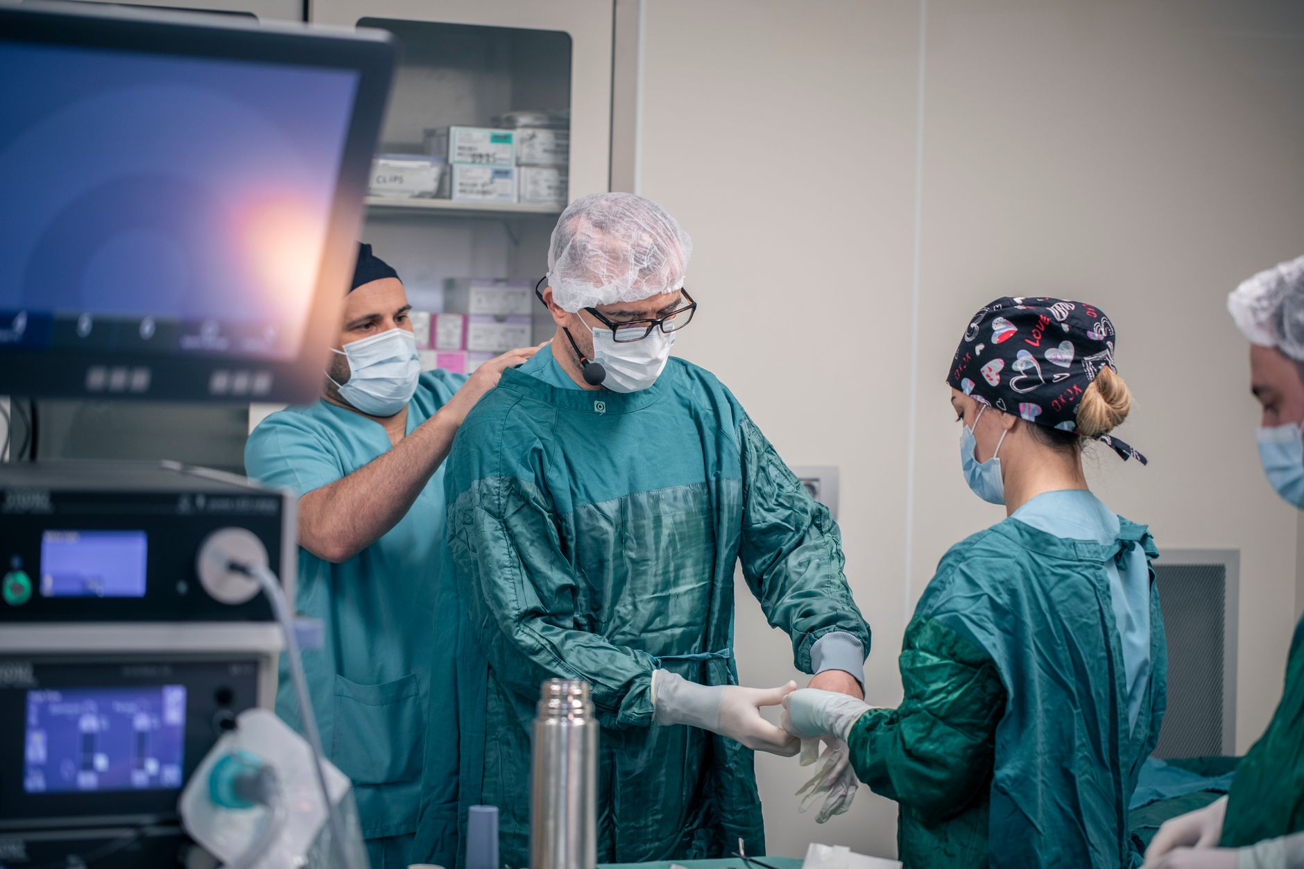 Medical professionals in scrubs and masks preparing for surgery in an operating room.