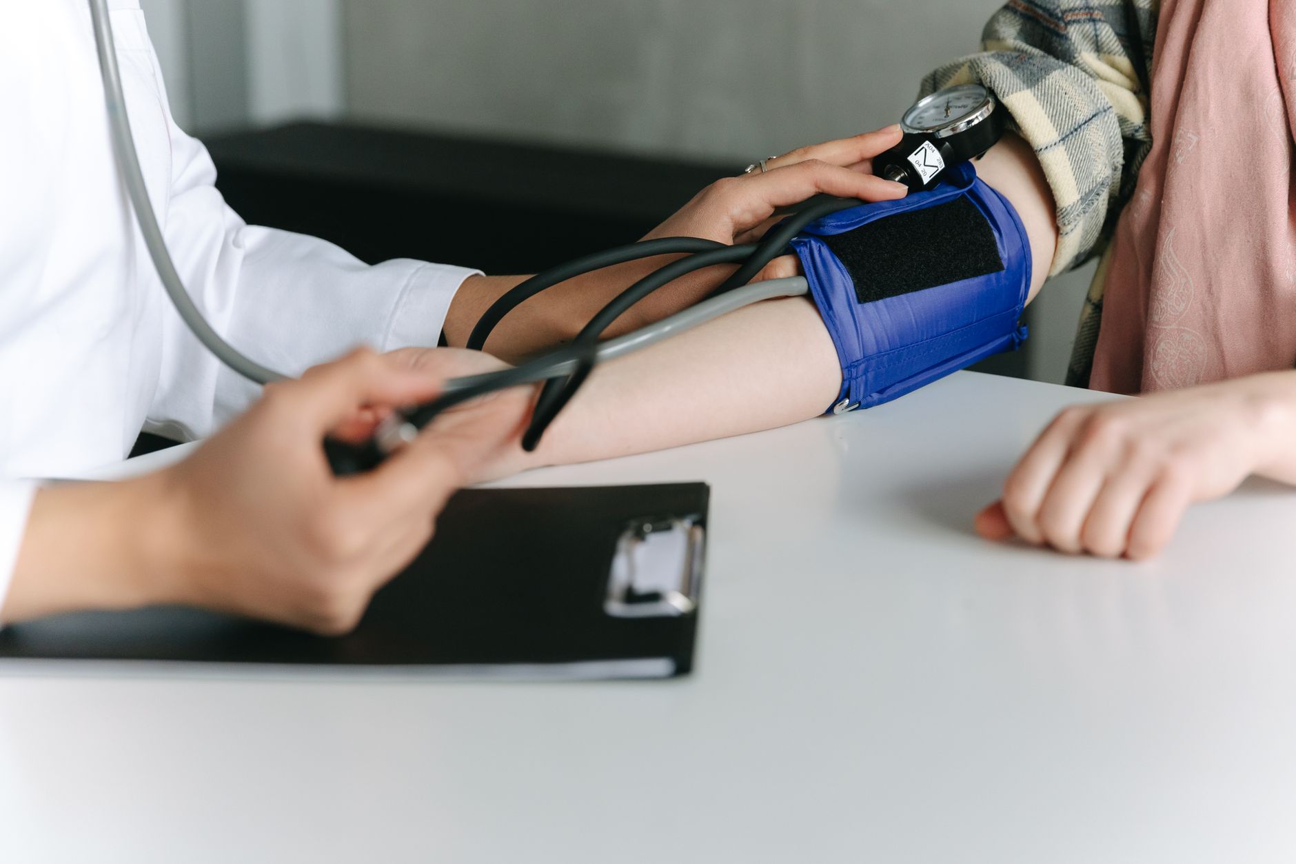 A doctor checks a child's blood pressure in a bright clinic room.