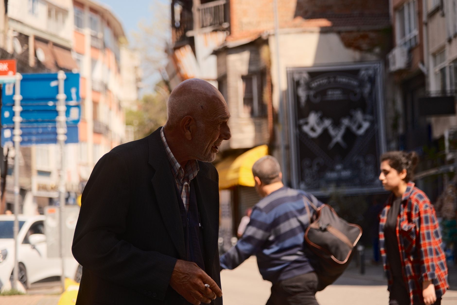 An elderly man walks in Istanbul, smiling and enjoying the sunny day.