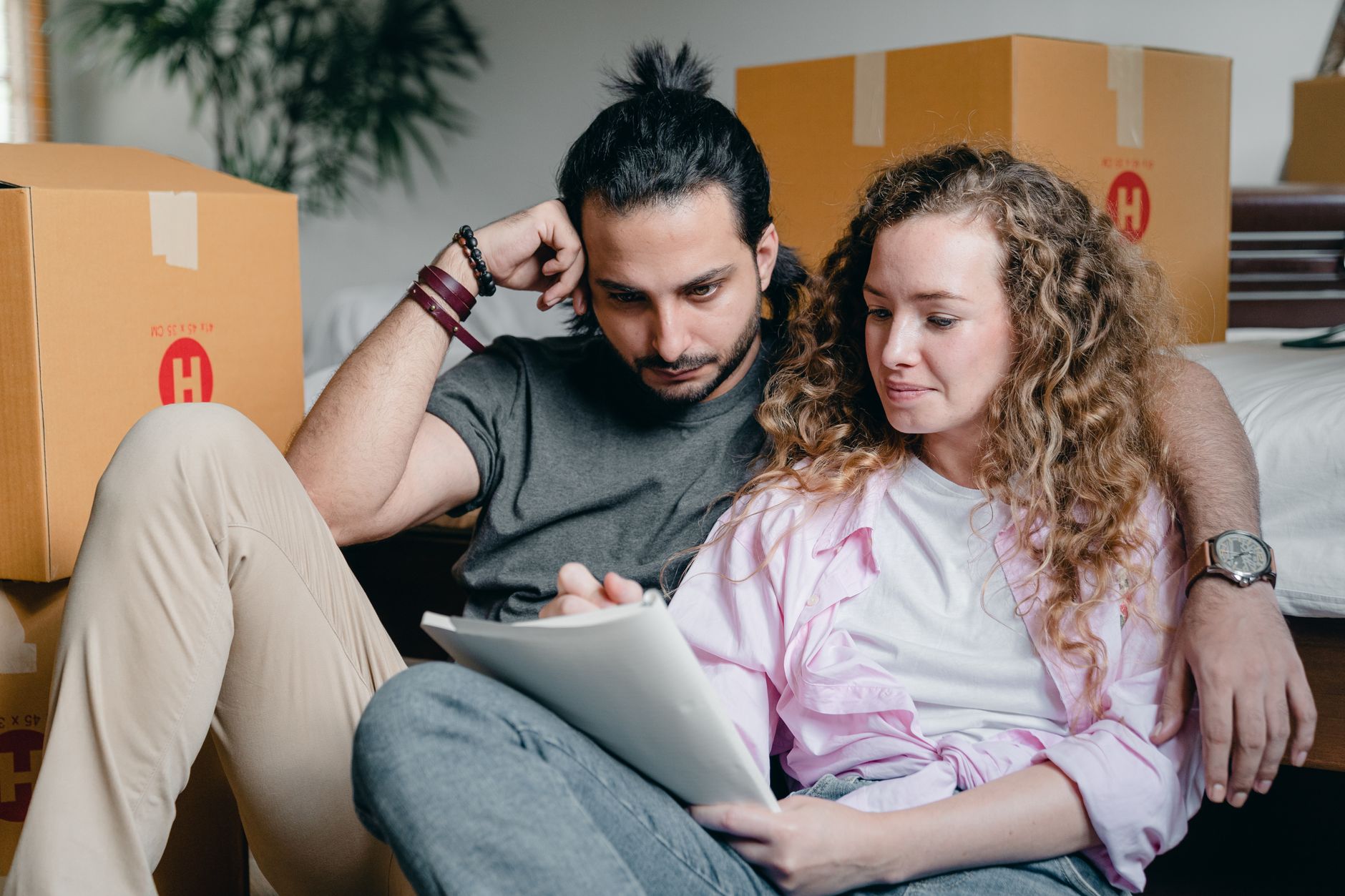 A couple sits together with a checklist, planning their move amidst cardboard boxes.