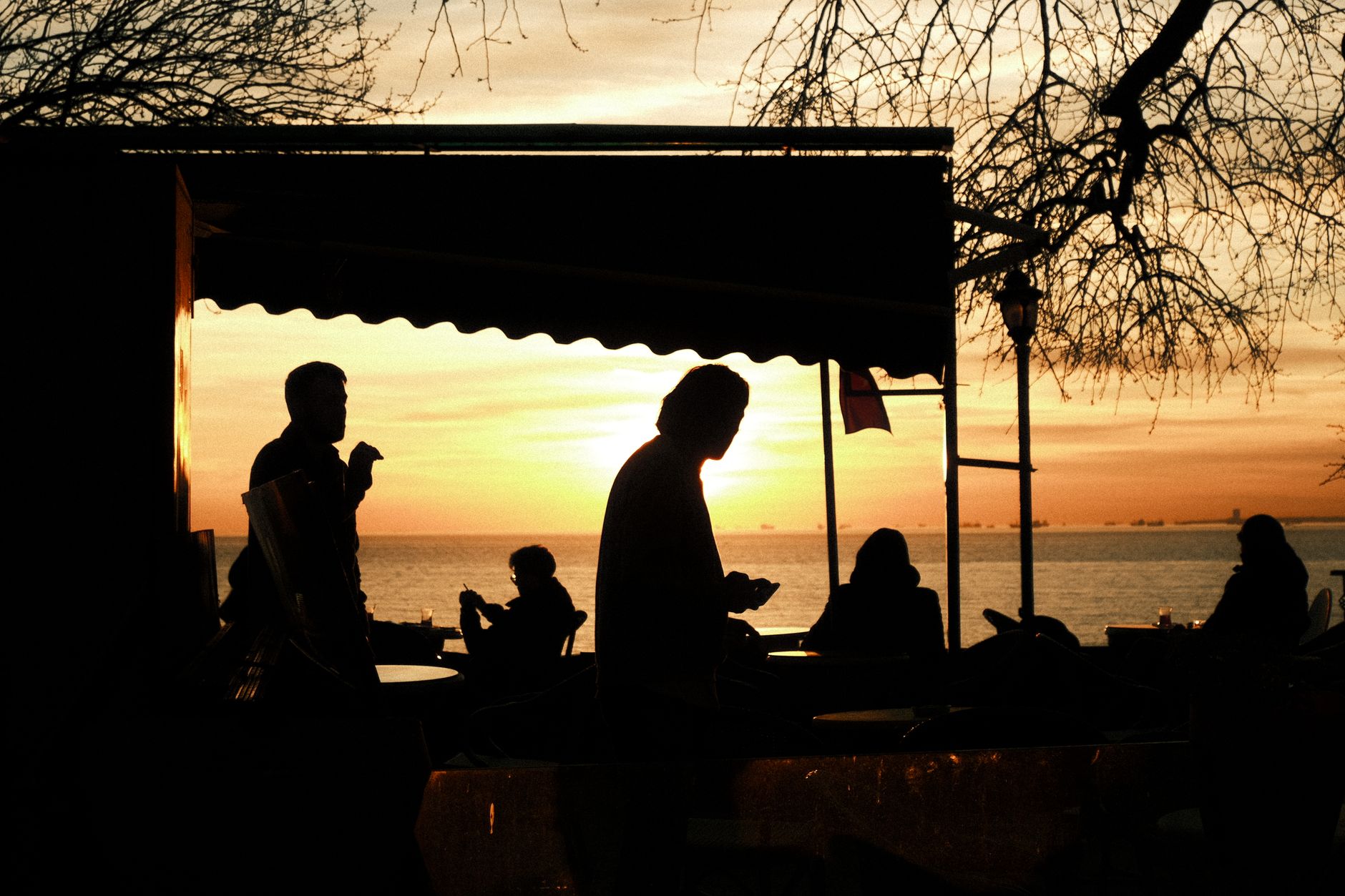 Silhouetted figures enjoying conversation at an Istanbul cafe during sunset.