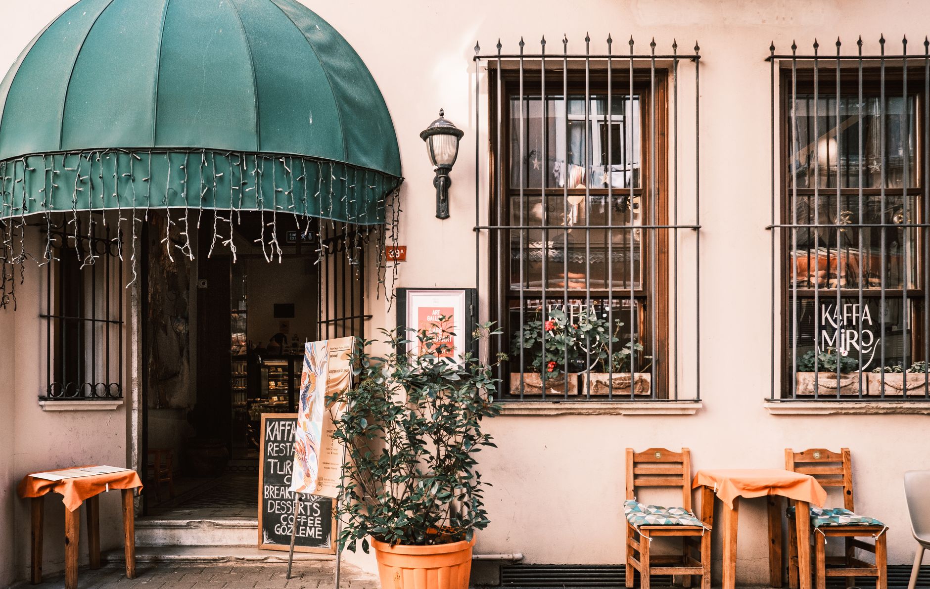 Colorful entrance of a cozy cafe in Istanbul, featuring a green canopy and outdoor tables.