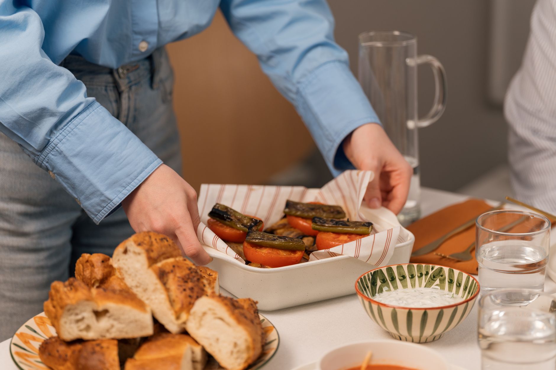 A person serves a plate of grilled vegetables and bread in a hospital room.