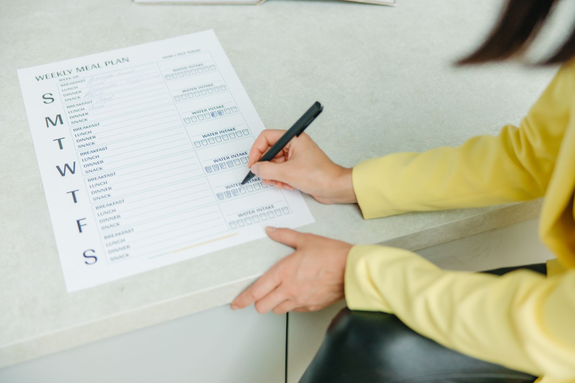 Close-up of hands writing a personalized meal plan on a clipboard.