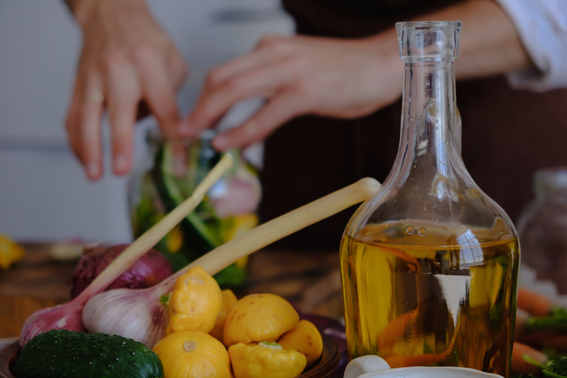 Hands preparing fresh vegetables and olive oil for a Turkish meal. Colorful ingredients are displayed.