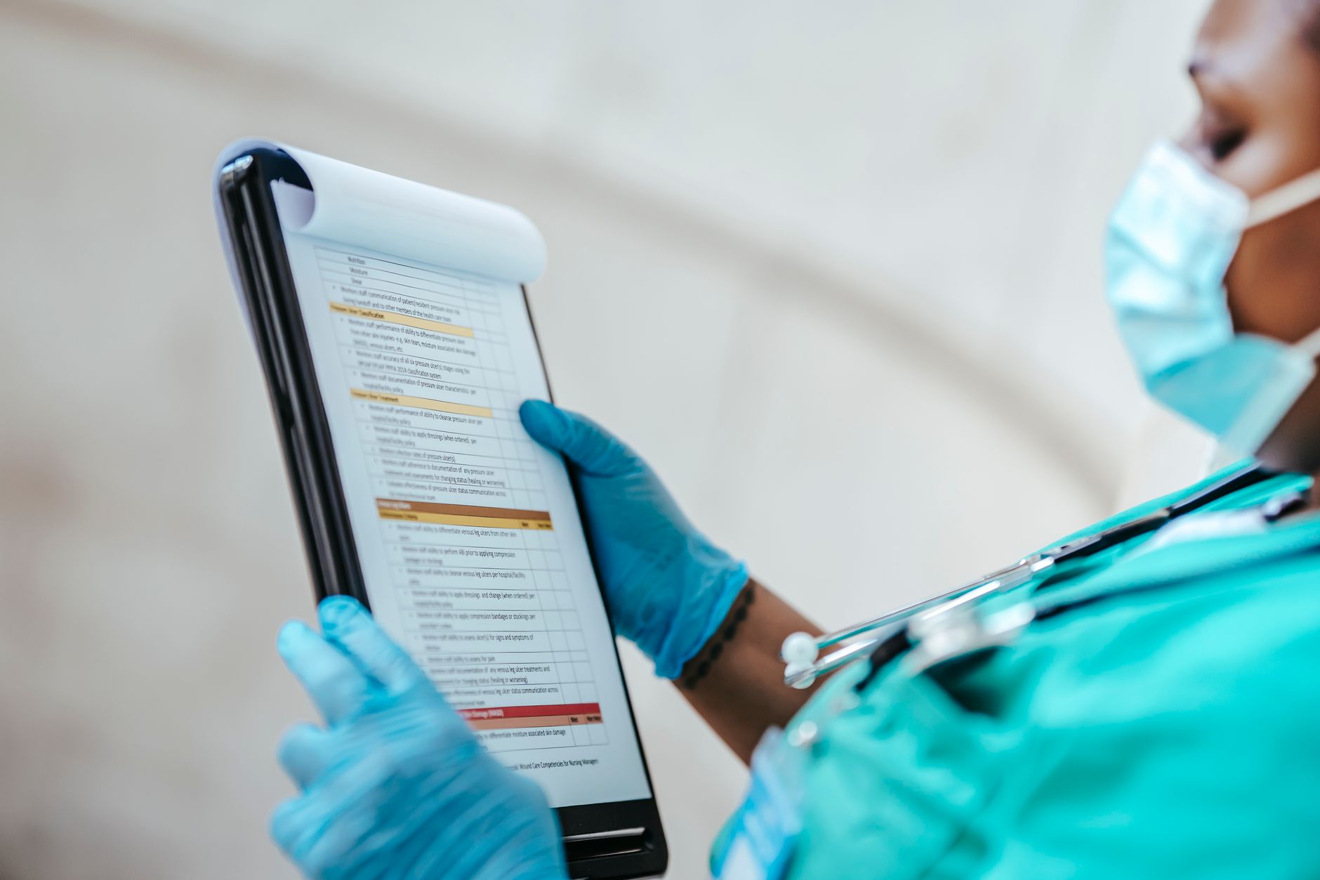 A healthcare worker in scrubs examines a pre-operative checklist on a digital tablet.