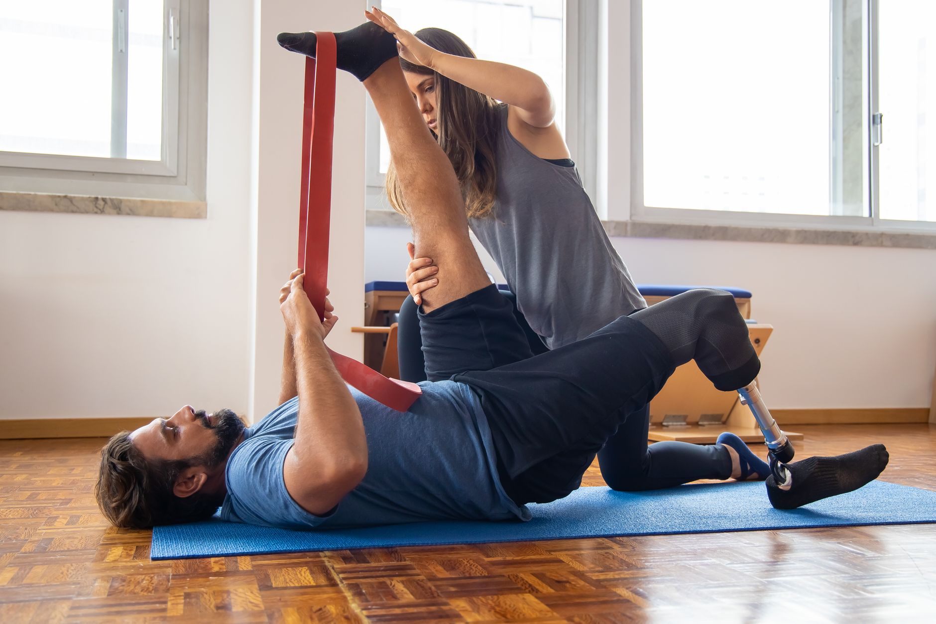 A physiotherapist assists a patient with mobility exercises using a resistance band.