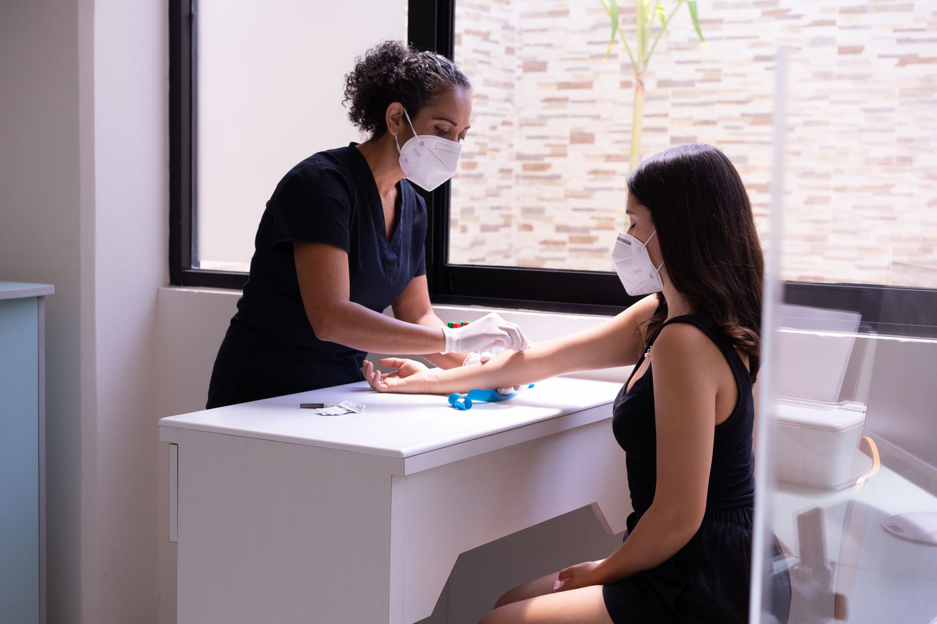 A healthcare worker assists a patient with a blood test in a clinic.