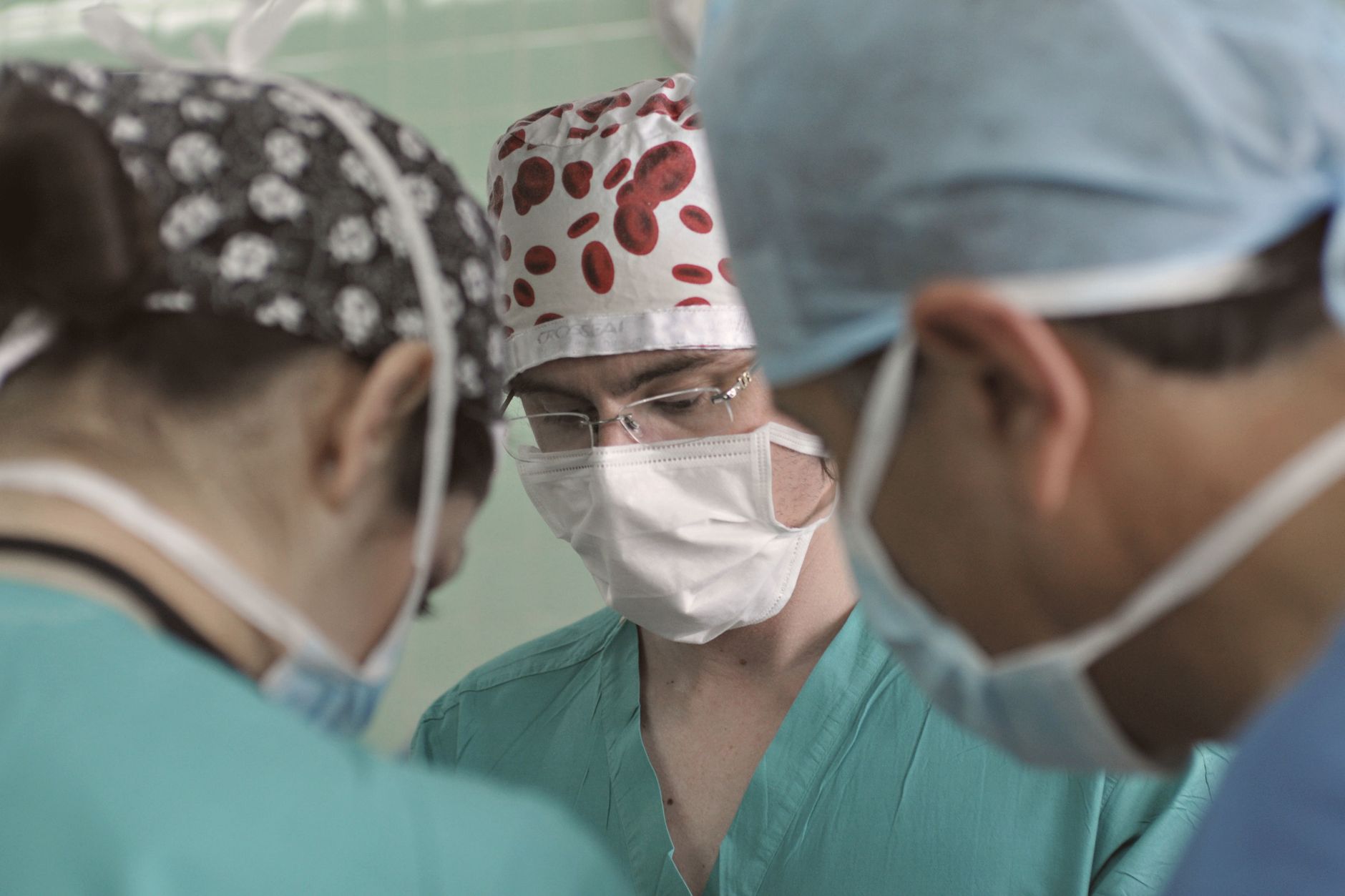 Medical professionals in scrubs and masks collaborating in surgery at a Turkish hospital.