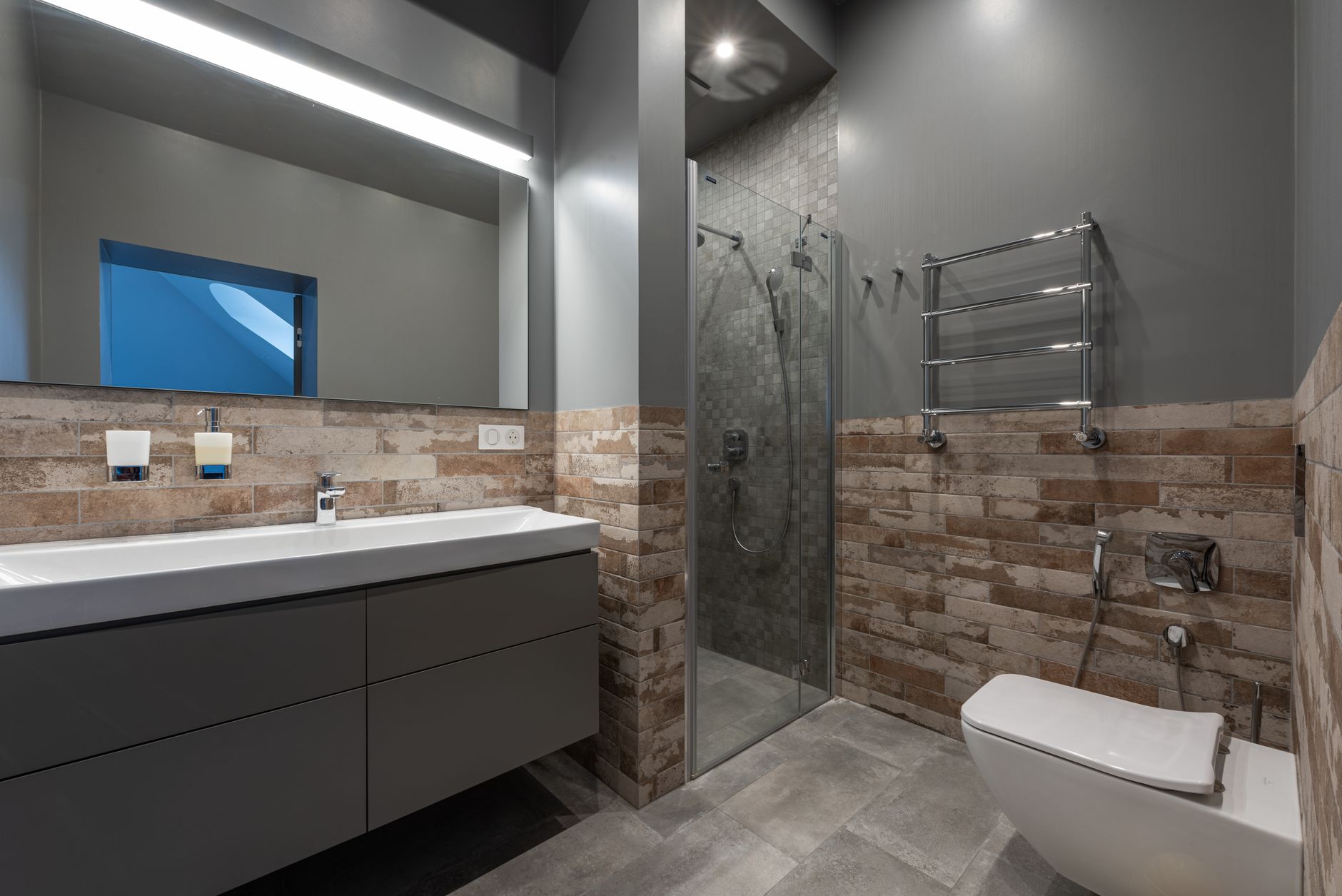 Stylish bathroom featuring a shower with safety grab rails and non-slip elements.