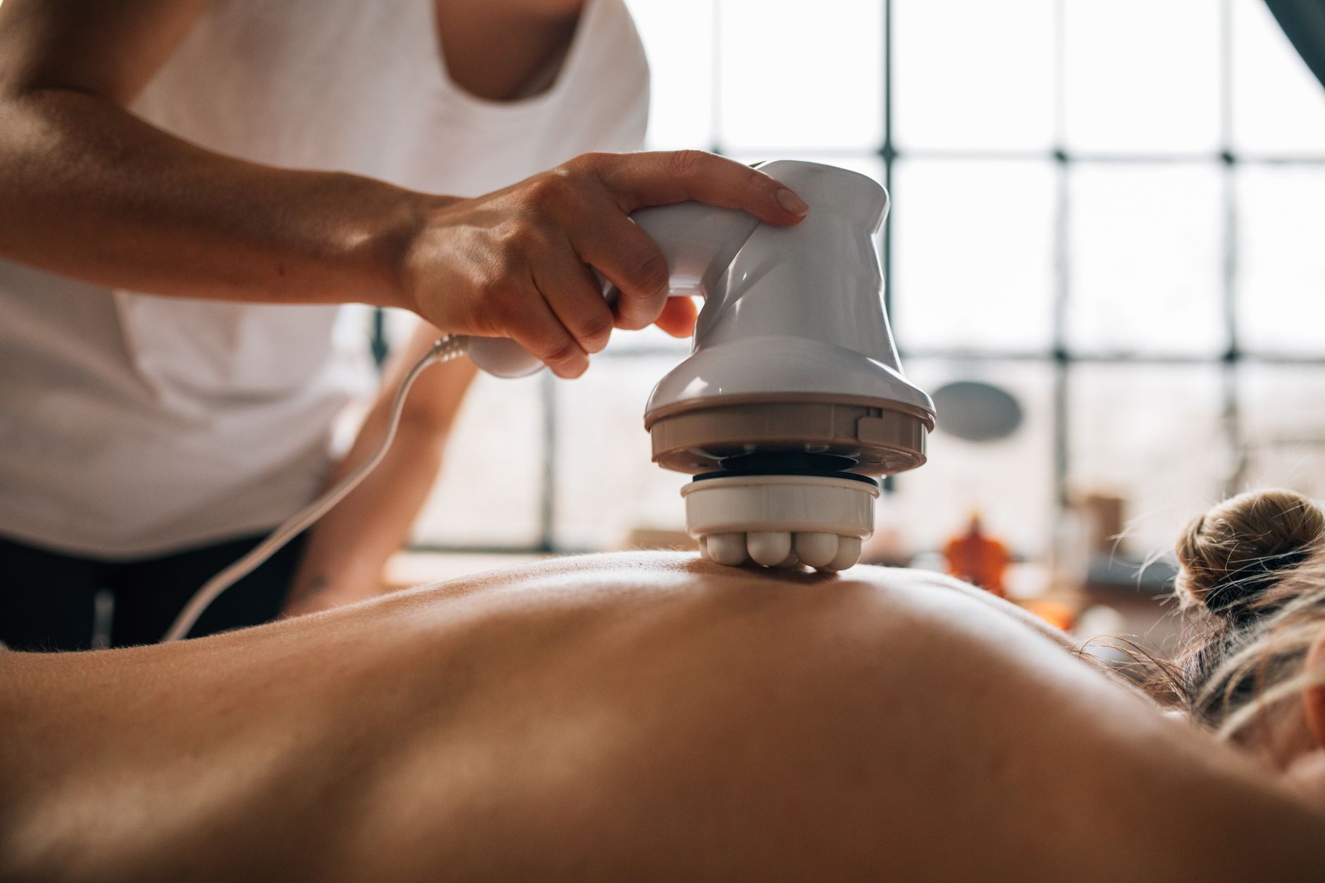 Therapist using a lymphatic drainage machine on a patient's back.