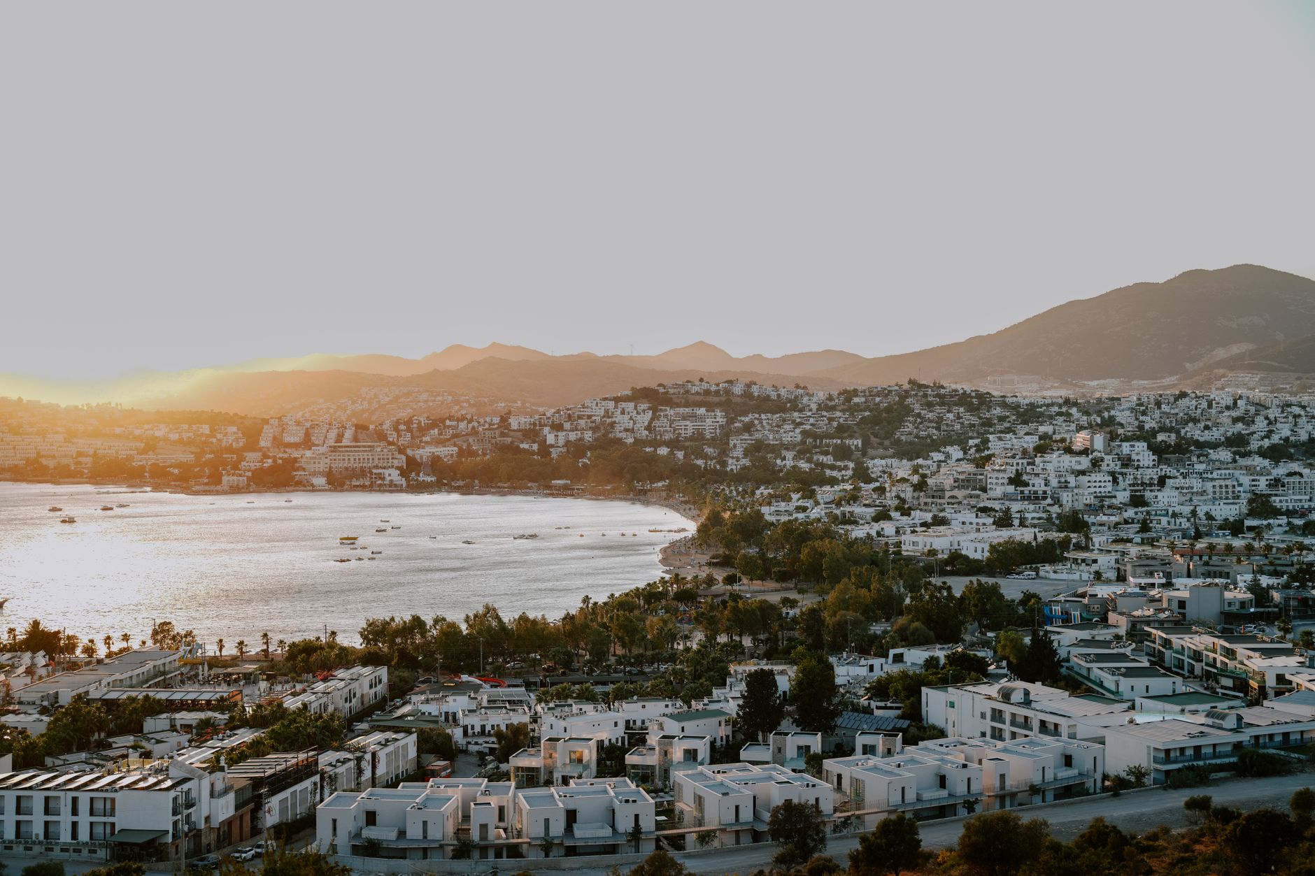 A serene sunset view over a Bodrum wellness resort, featuring white buildings and a tranquil bay.