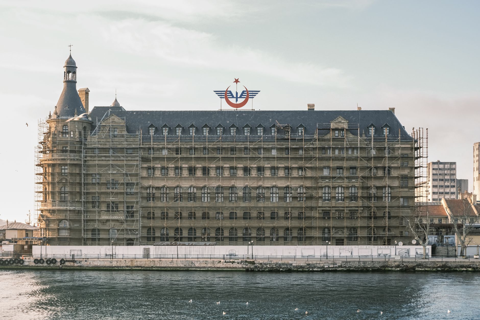View of a renovated hospital in Istanbul, surrounded by scaffolding beside the water.