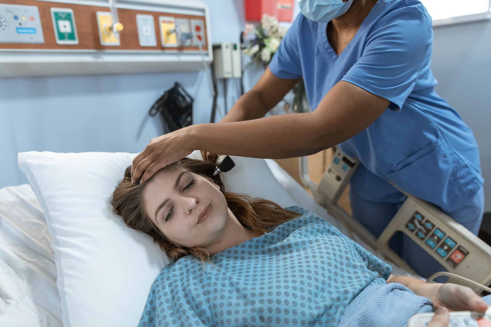 A nurse caring for a patient lying in a hospital bed, offering in-room support.