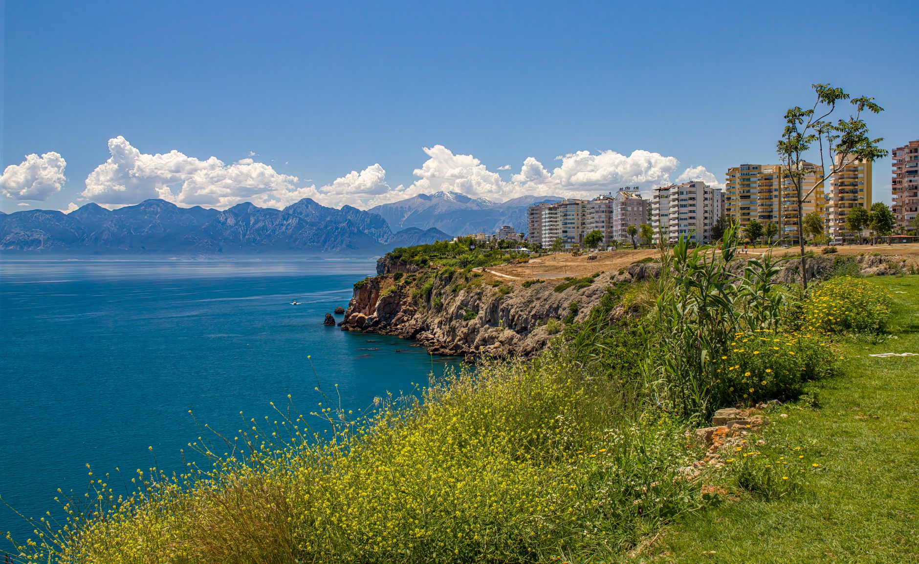 Stunning coastal view in Antalya, showcasing cliffs, blue waters, and modern apartments.