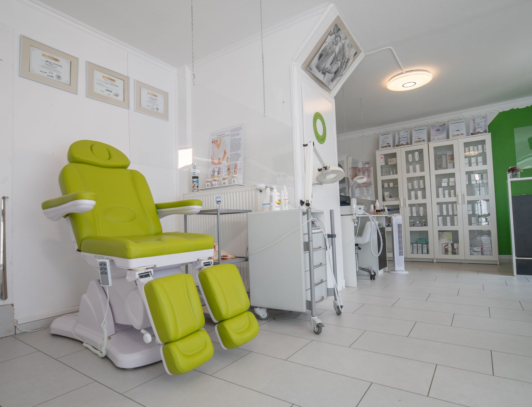 Bright and modern rhinoplasty clinic interior featuring a green treatment chair and display cabinets.