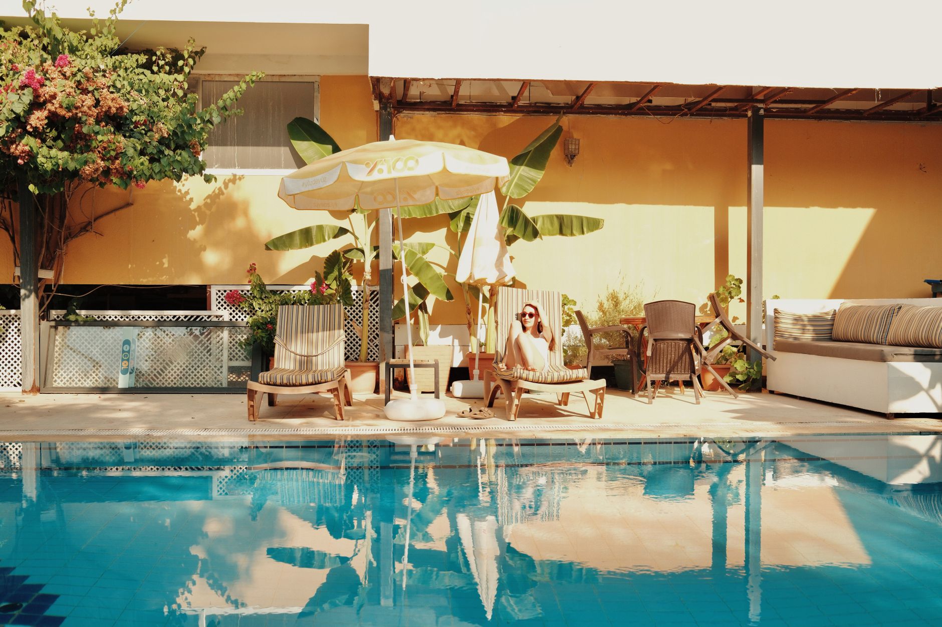 A patient relaxes poolside at a luxurious resort, enjoying the sunlight and tropical plants.