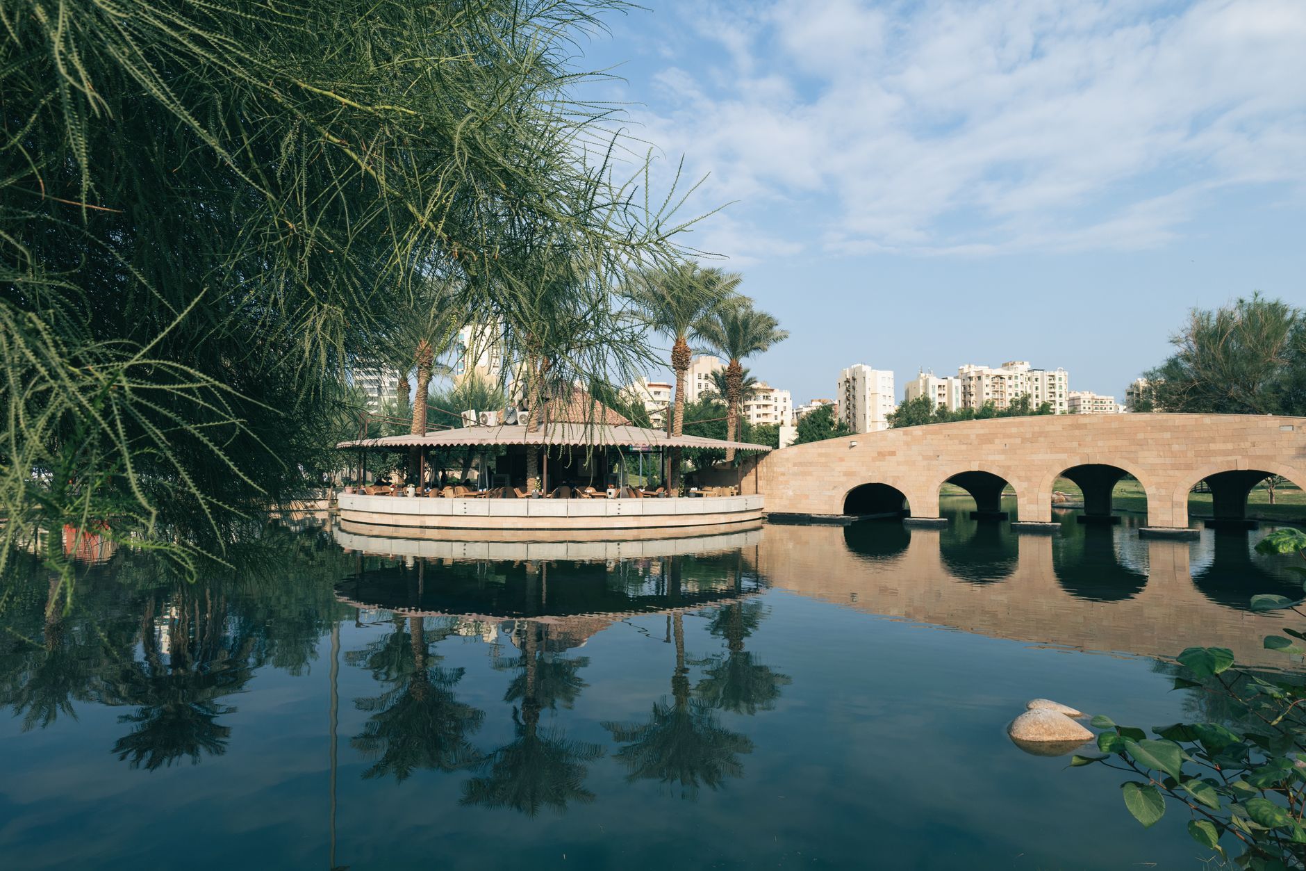 A tranquil riverside café in Eskişehir reflecting in calm waters, surrounded by greenery.
