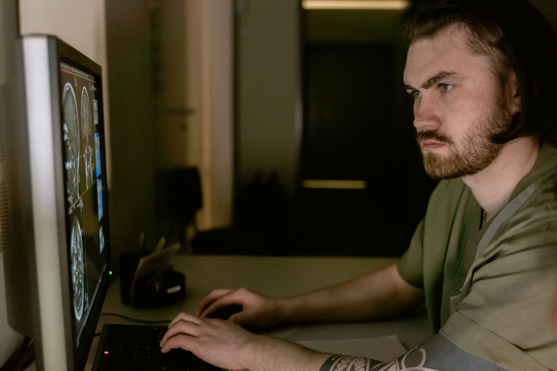 A medical professional analyzing 3D imaging data on a computer in a dimly lit lab.