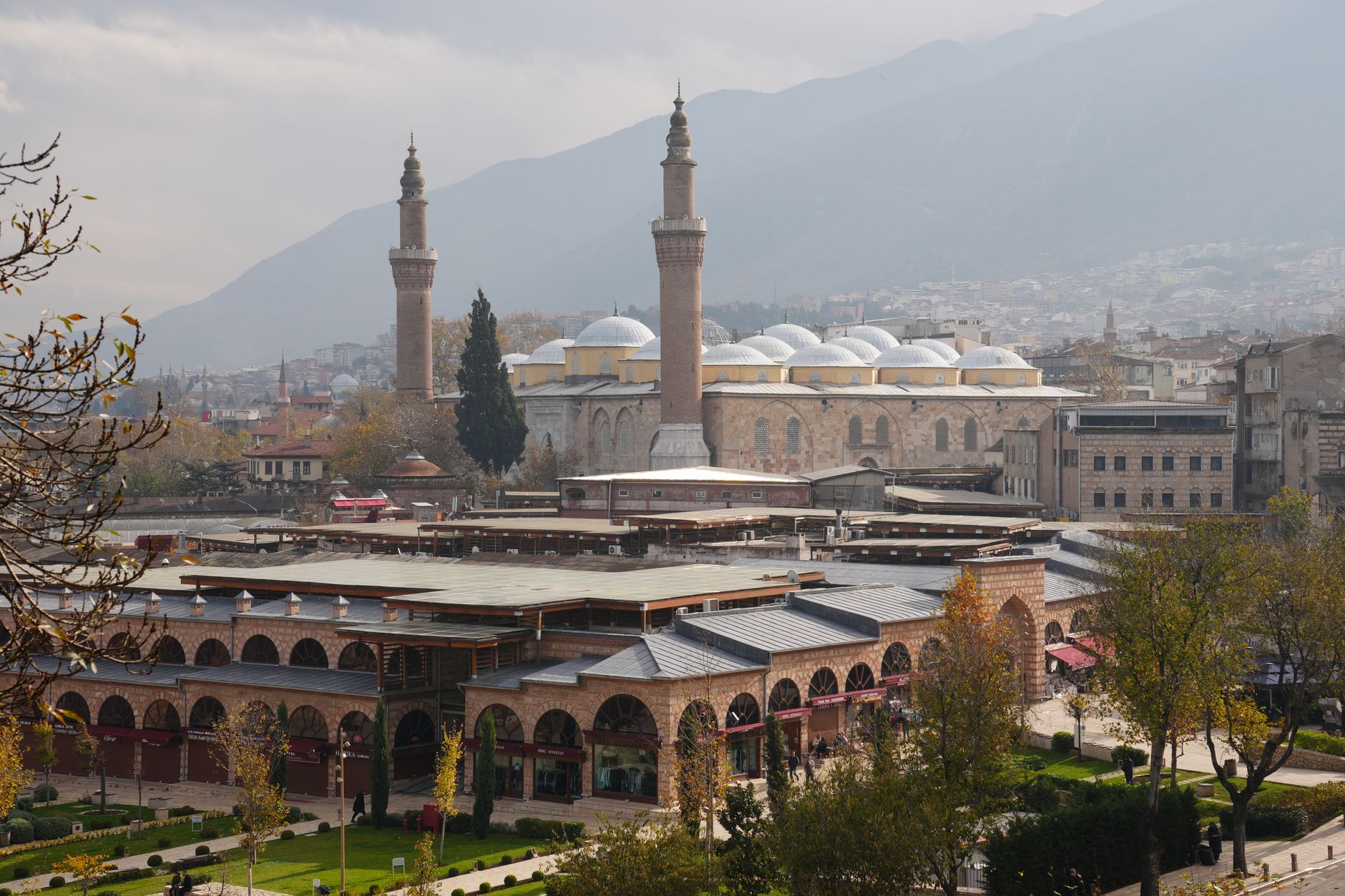A panoramic view of Bursa featuring historic mosques and traditional architecture amid mountains.
