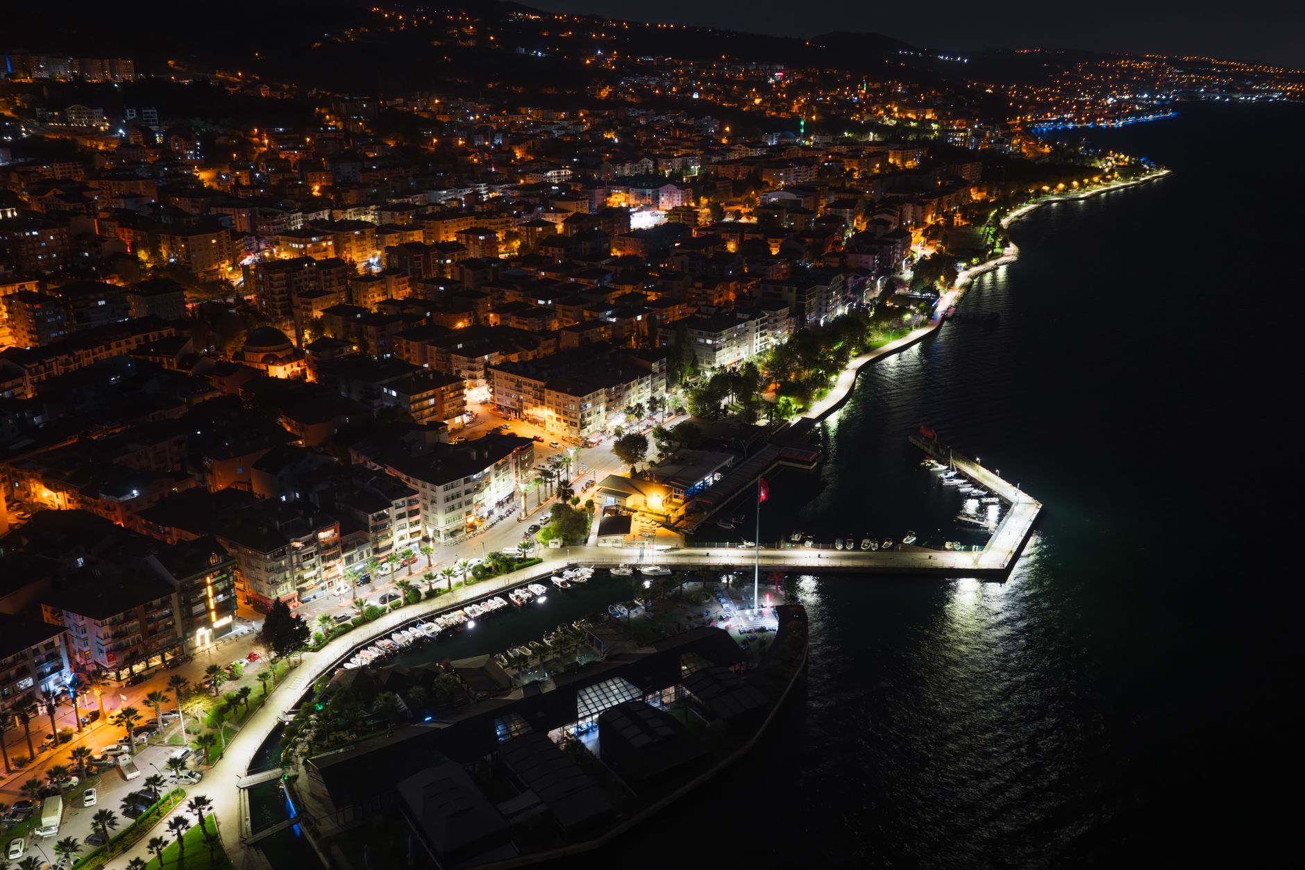 Night view of Kocaeli's waterfront, featuring illuminated buildings and a serene walkway along the Marmara Sea.