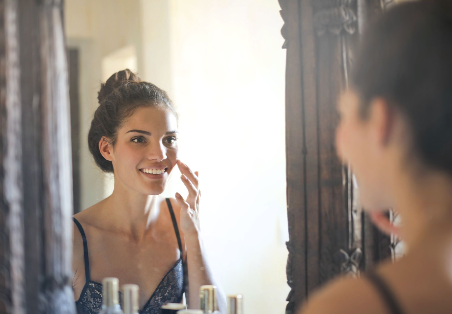 A woman admires her reflection, smiling contentedly after rhinoplasty.