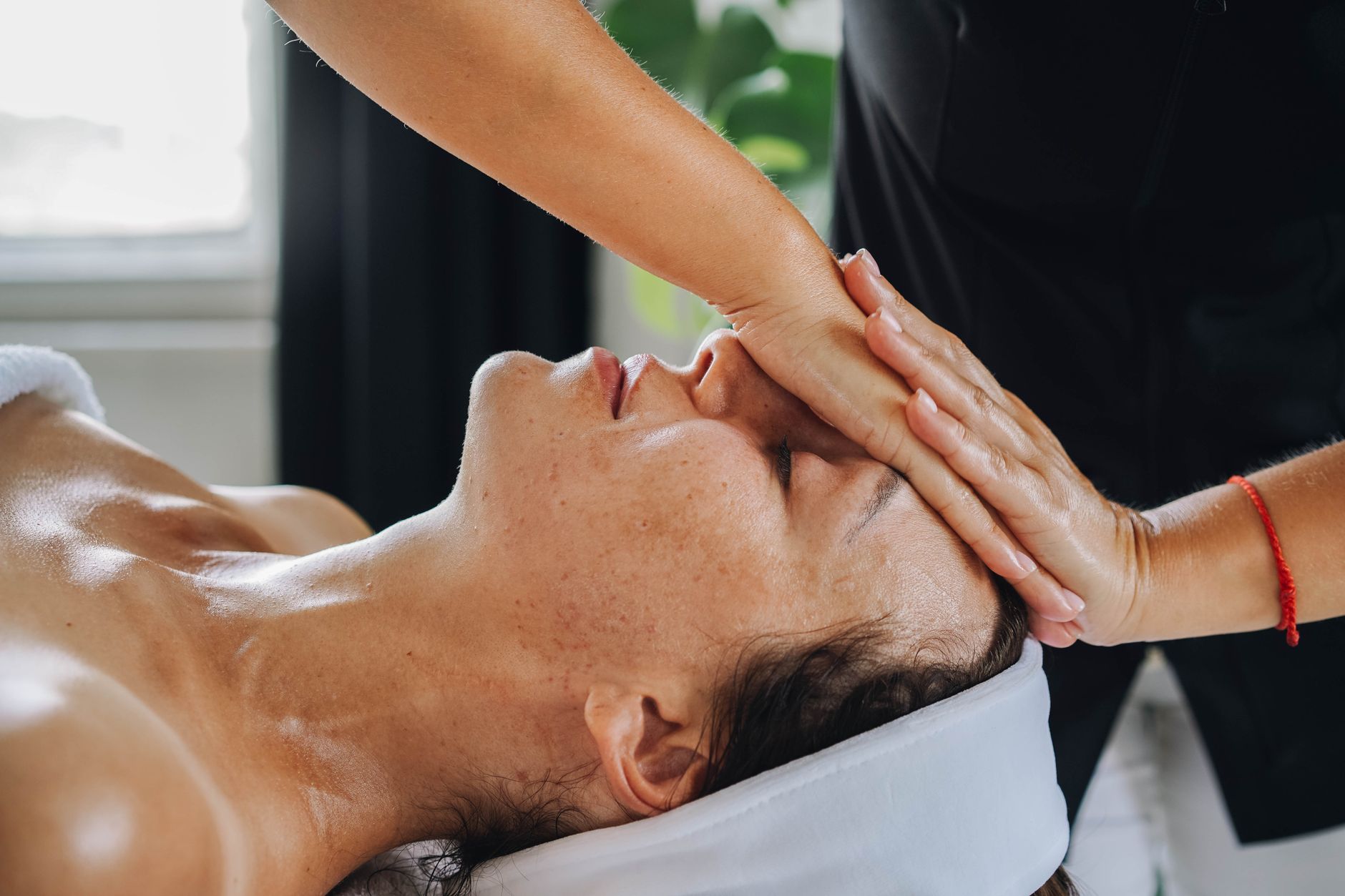 Therapist performing lymphatic drainage massage on a relaxed patient’s face.