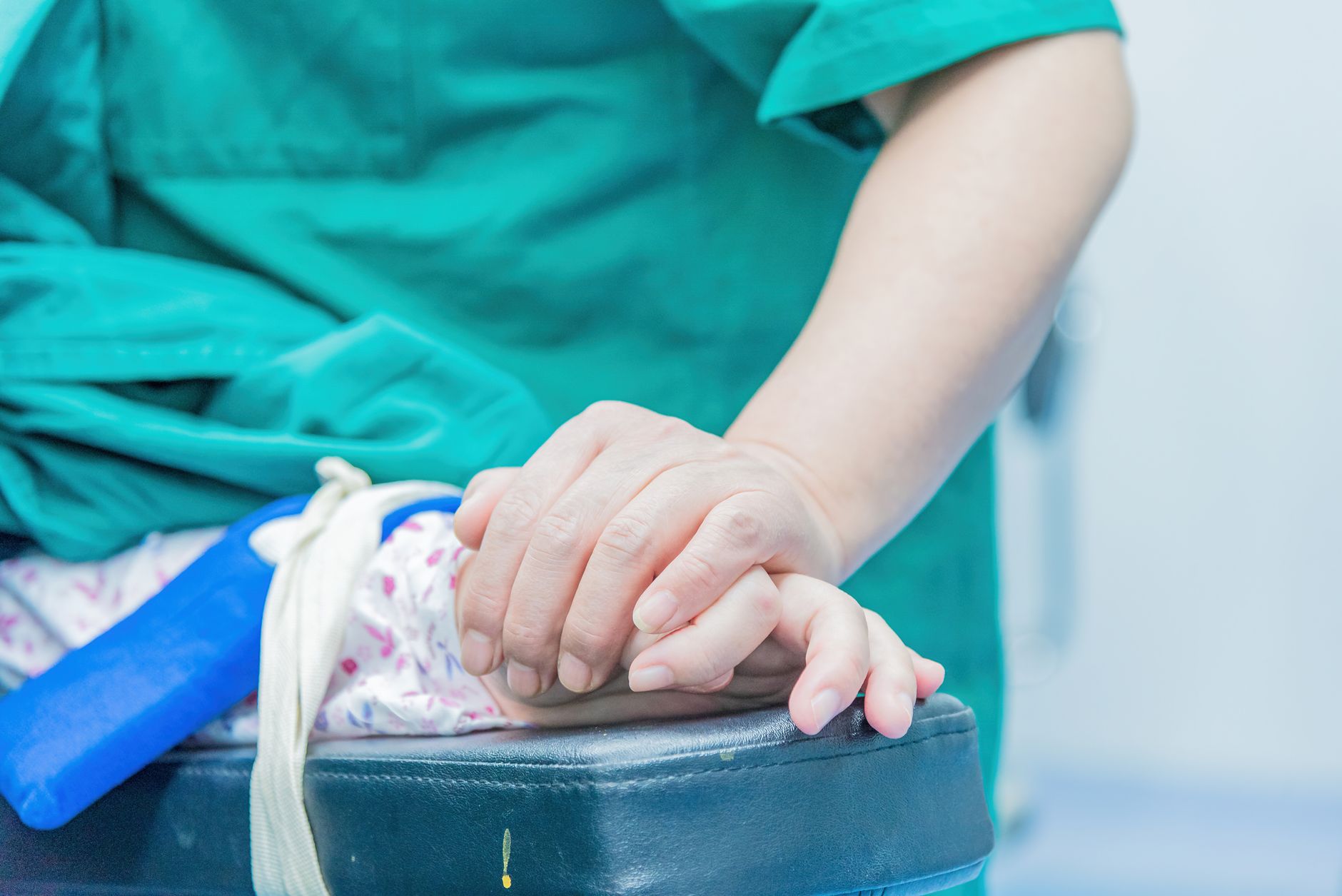 A comforting moment in surgery with hands gently held, providing support.