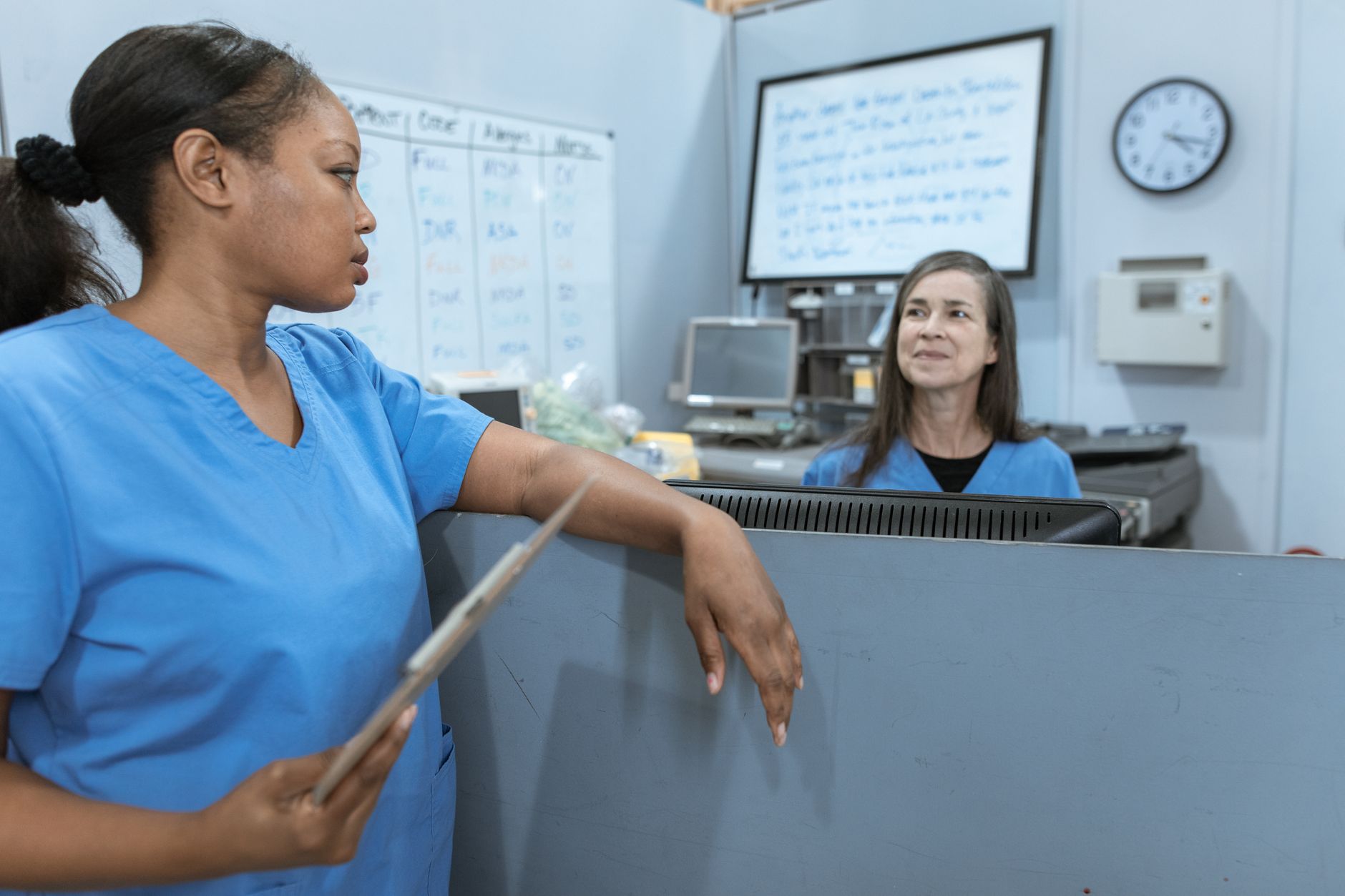 Two nurses in scrubs discussing post-operative care strategies in a healthcare setting.