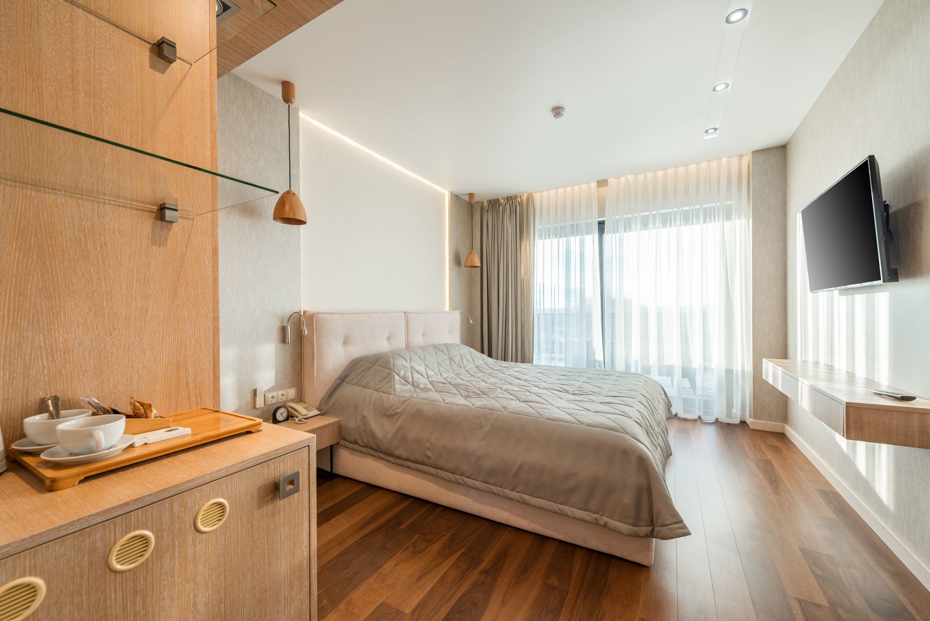 Comfortable hospital room featuring a bed, wooden decor, and large windows.