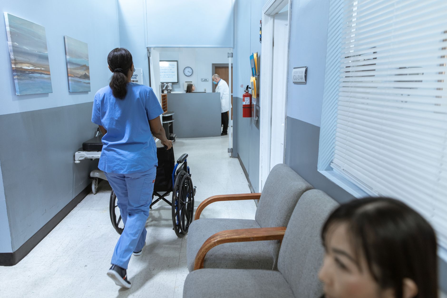 A nurse pushes a wheelchair through a hospital corridor, aiding recovery.