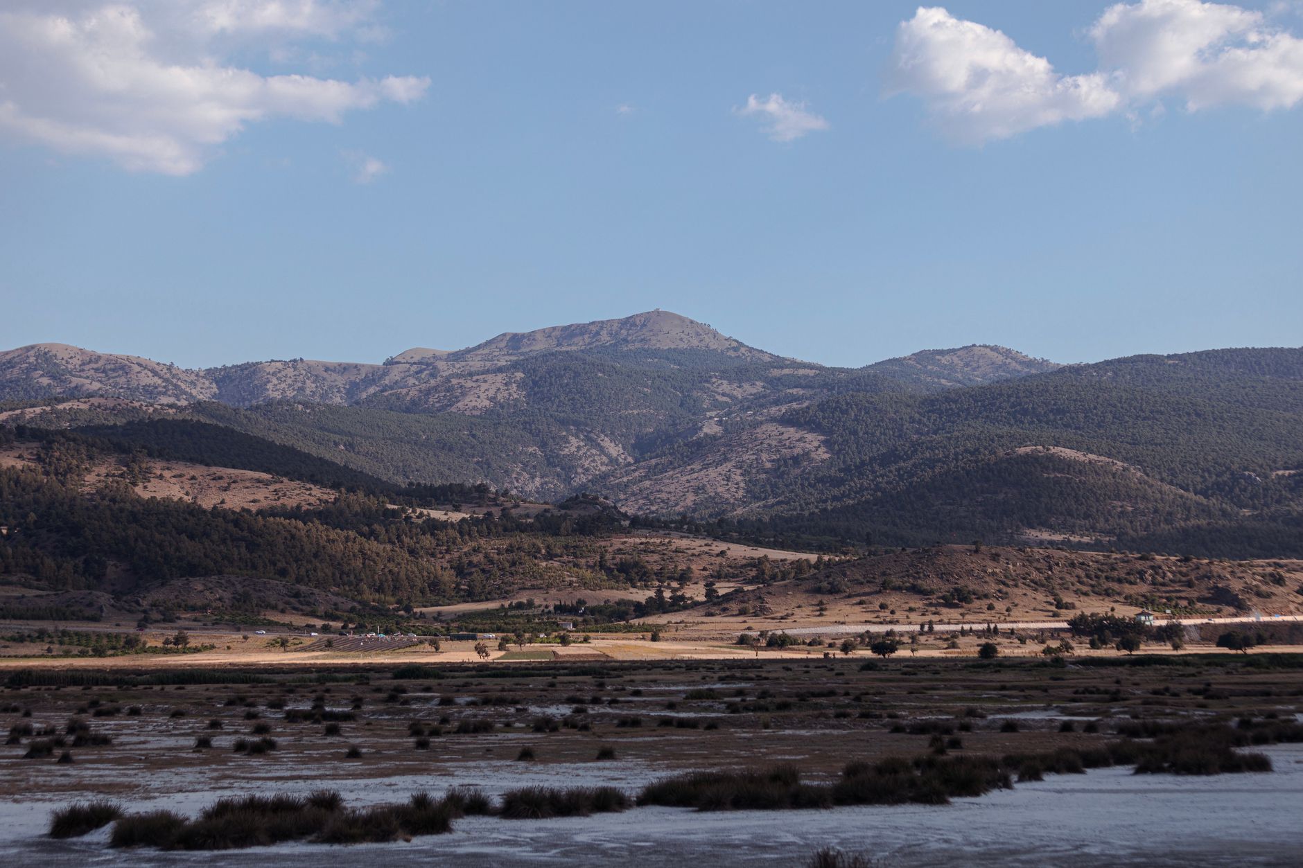 A picturesque view showcasing Lake Eğirdir and the majestic mountains nearby, with clear skies and sparse clouds.