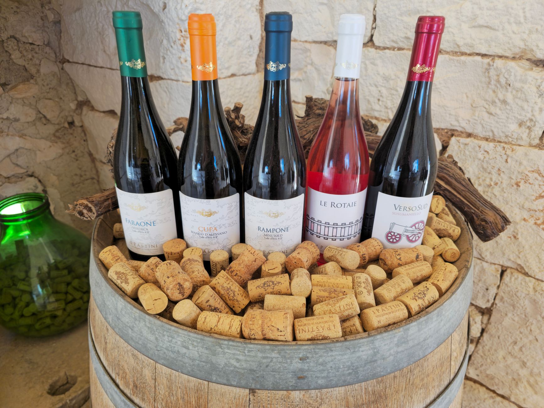 Five bottles of local wines displayed over corks at an Italian vineyard.