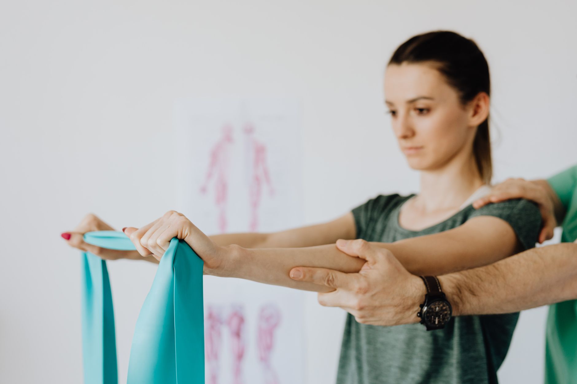 A physiotherapist helps a young patient with resistance bands in a therapy session.
