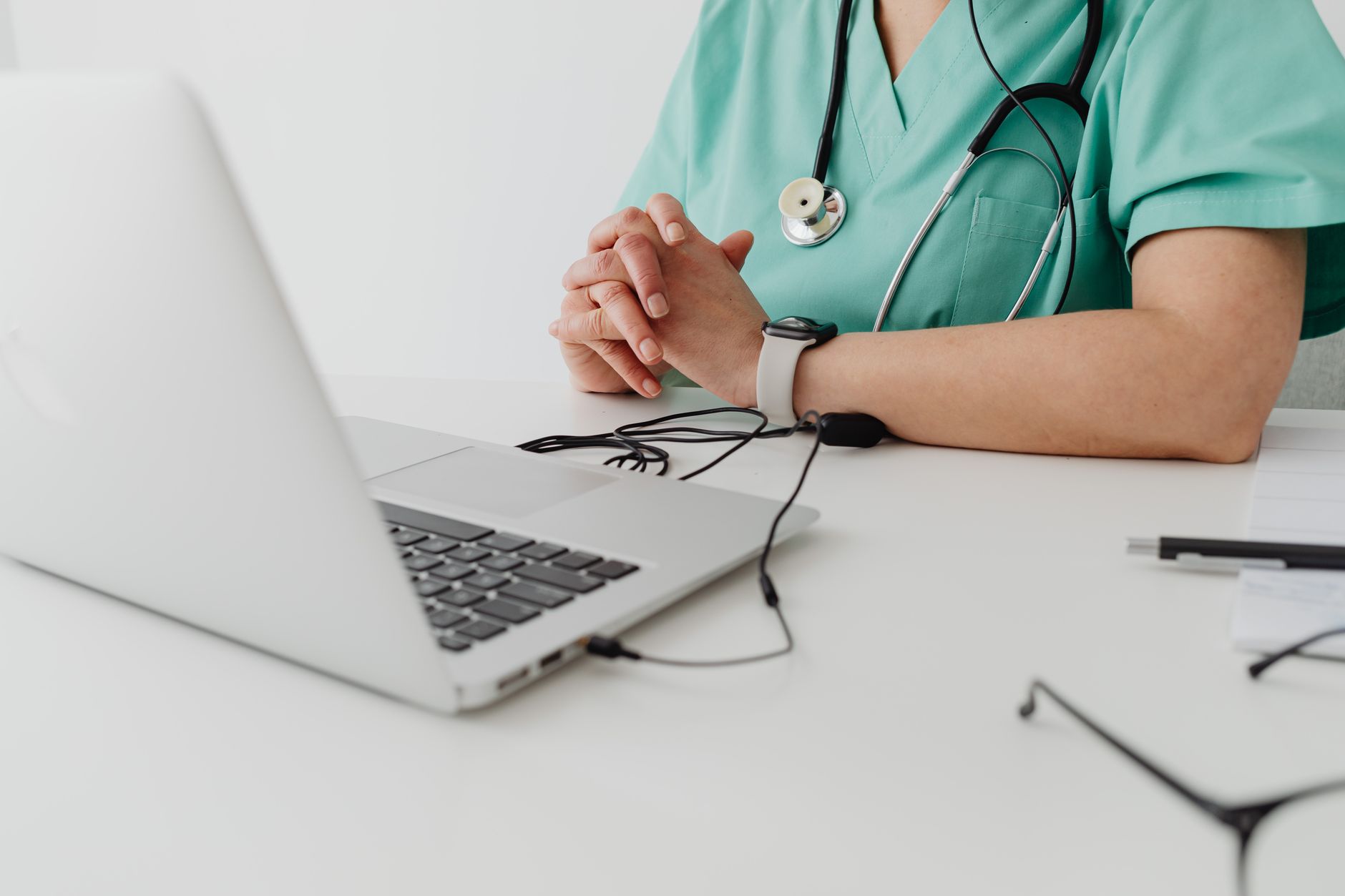 Close-up of a healthcare worker in scrubs using a laptop, emphasizing secure digital health record sharing.