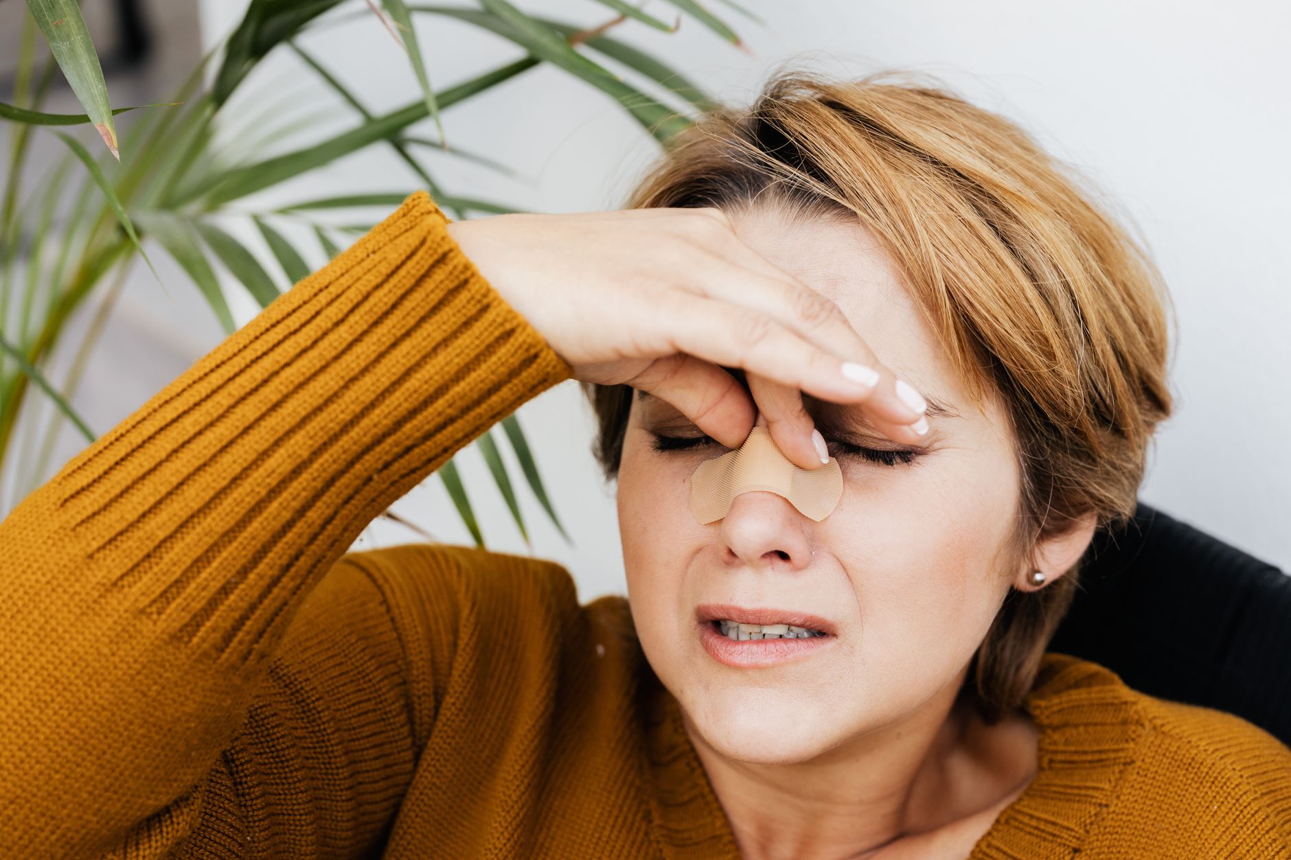 A woman resting with a nasal splint after septoplasty, showing signs of early recovery.