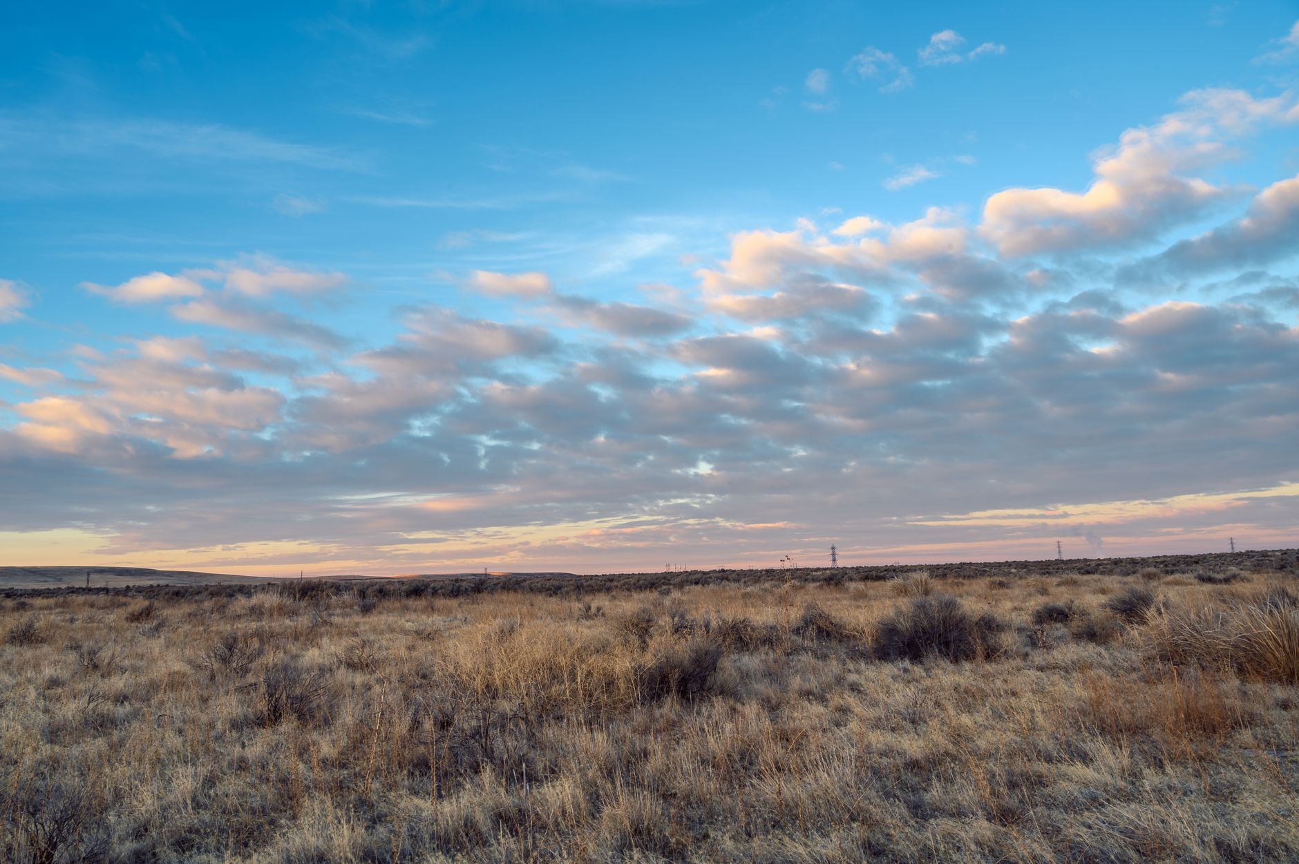 A scenic view of the Sivas steppe at sunset, featuring rolling hills and a dramatic sky filled with clouds.