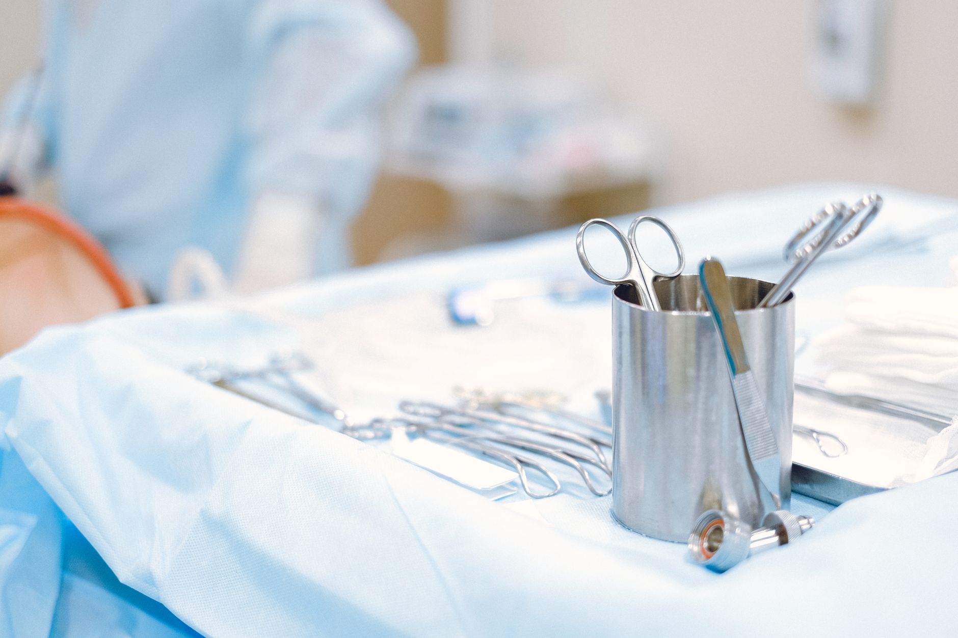 Surgical instruments arranged on a blue draped table in an operating room.