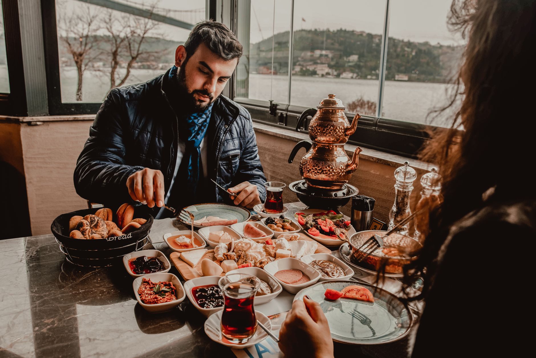 İstanbul'da kuymak, çay ve çeşitli yan yemeklerden oluşan geleneksel Türk kahvaltısının tadını çıkaran bir adam.